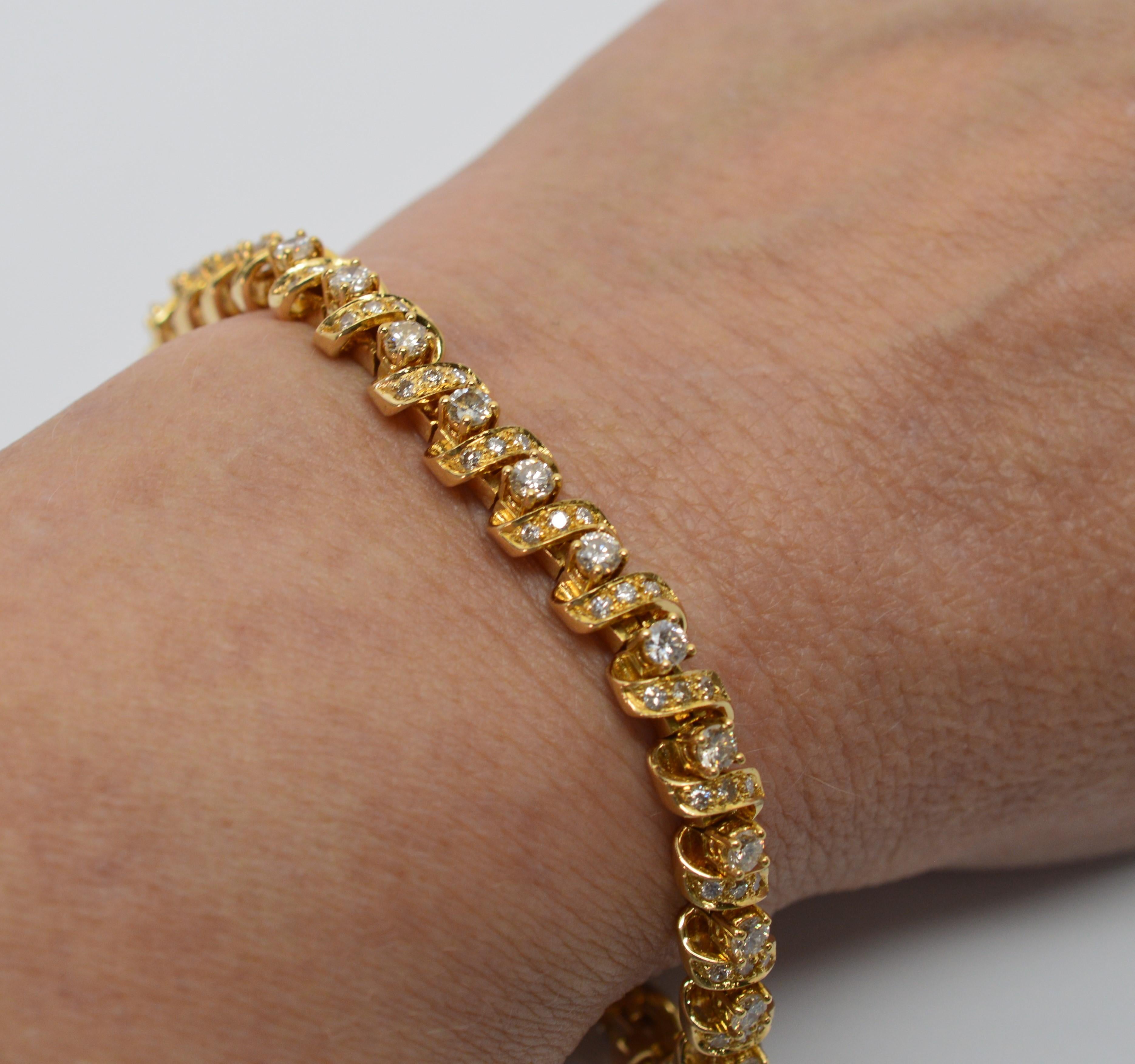 This timeless eighteen karat 18K yellow gold tennis bracelet boasts twenty nine prong set H/SI diamonds wrapped with a ribbon of eighteen carat 18K yellow gold sprinkled with yet more diamonds! In mint condition and finished with a box clasp and two