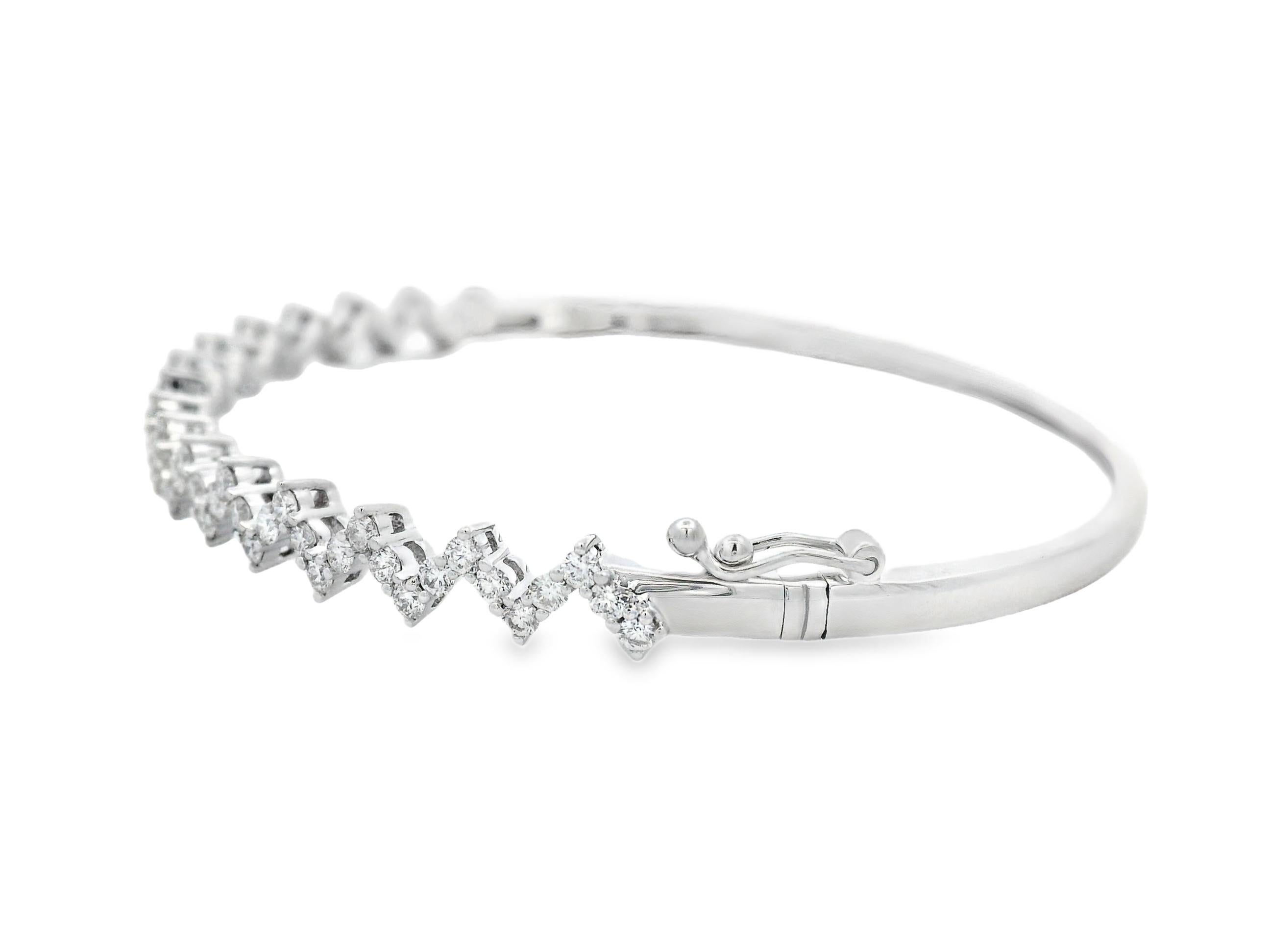 This contemporary diamond bangle bracelet features a striking zigzag motif adorned with sixty-three round brilliant-cut diamonds totaling approximately 1.20 carats. Each diamond is precisely prong-set in 14K white gold, creating a rhythmic pattern