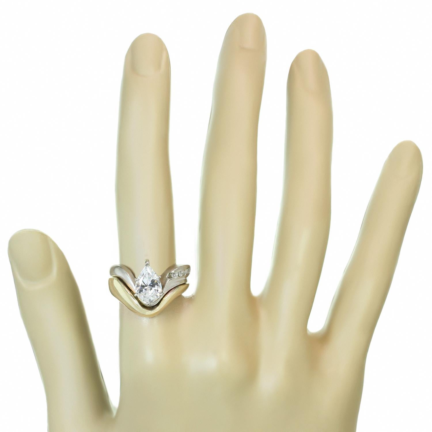 This elegant engagement ring is crafted in 14k yellow gold in shiny and satin finish and set with a white zircon pear-cut centerstone accented with row of round diamonds. The H VS2-SI1 diamonds weigh an estimated 0.20 carats. Made in United Kingdom