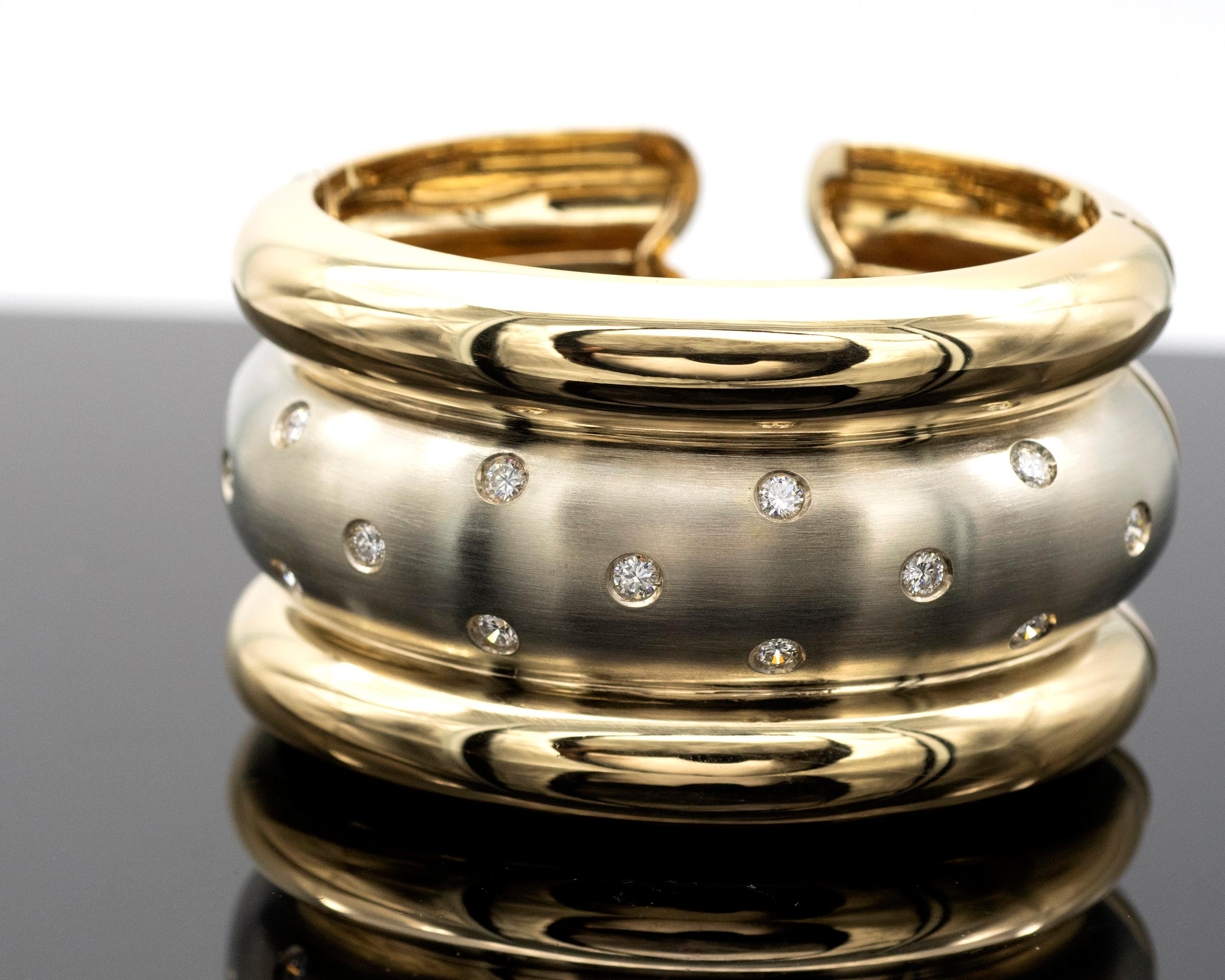 Magnifique bracelet manchette moderne à deux tons. La partie centrale est en or blanc satiné serti de diamants, entourée de deux bandes d'or jaune brillant. Le contraste qui en résulte est très élégant. 
La marque est excellente 

Diamants : 15