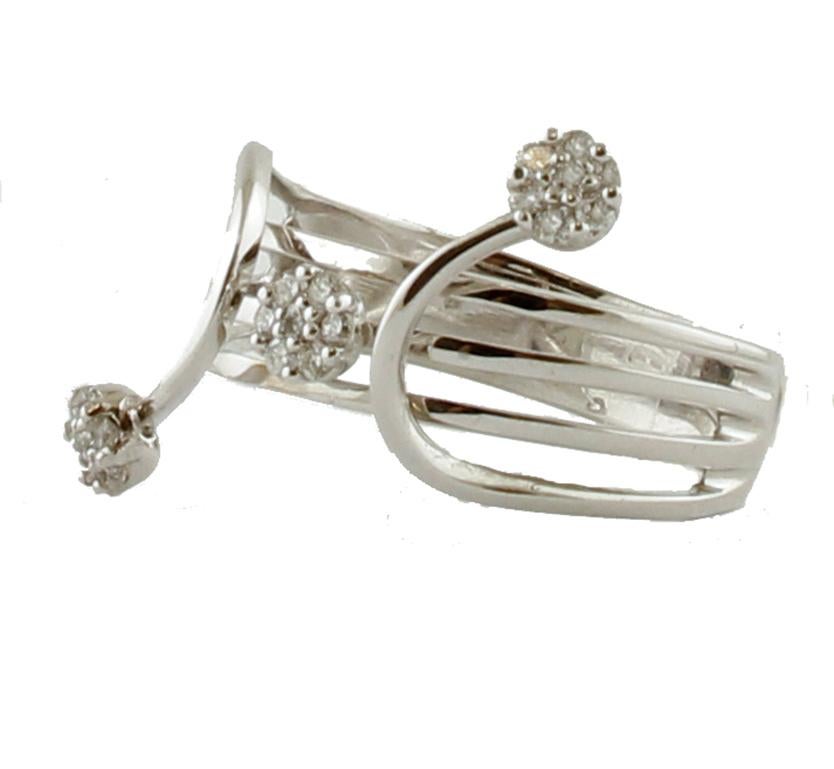 Bello  anello a fascia in oro bianco 18 kt a struttura incrociata realizzato con tre piccoli fiori tempestati di piccoli diamanti bianchi.
Questo anello è realizzato completamente a mano da maestri orafi italiani.
Diamanti 0.23 ct, taglio brillante,