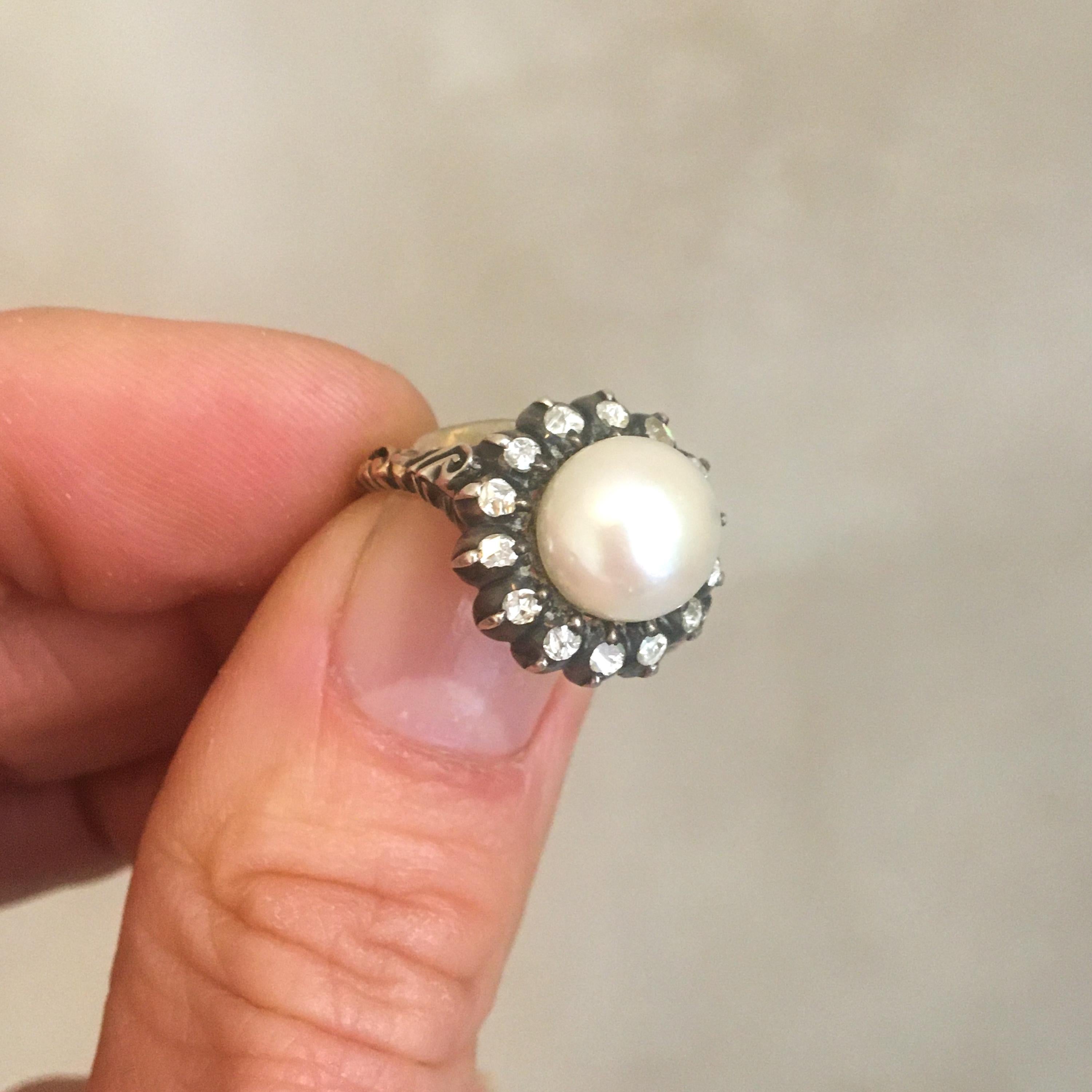This gorgeous early 20th century pearl and diamond jewelry set consisting of two round stud earrings and a ring. The ring and earrings are each set with fourteen rose cut diamonds and surrounding a beautiful round cultured pearl. The band of the