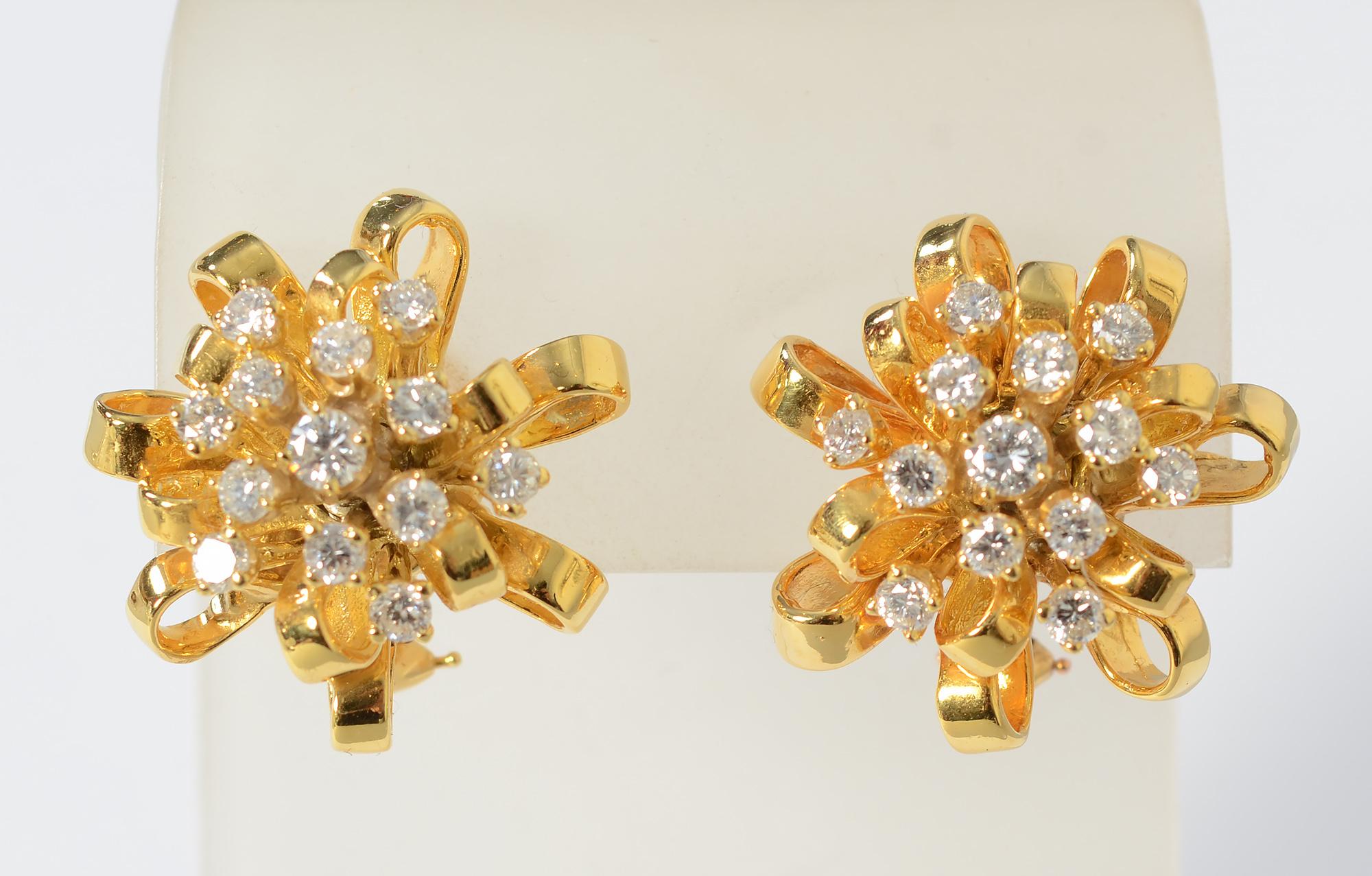 Elegante und verspielte Ohrringe aus 18 Karat Gold mit je 13 Diamanten. Die goldenen Loops sehen aus wie Teil einer dekorativen Geschenkverpackung. Die Diamanten haben ein Gesamtgewicht von 2,5 Karat und sind von der Farbe G und der Qualität VS.
Die