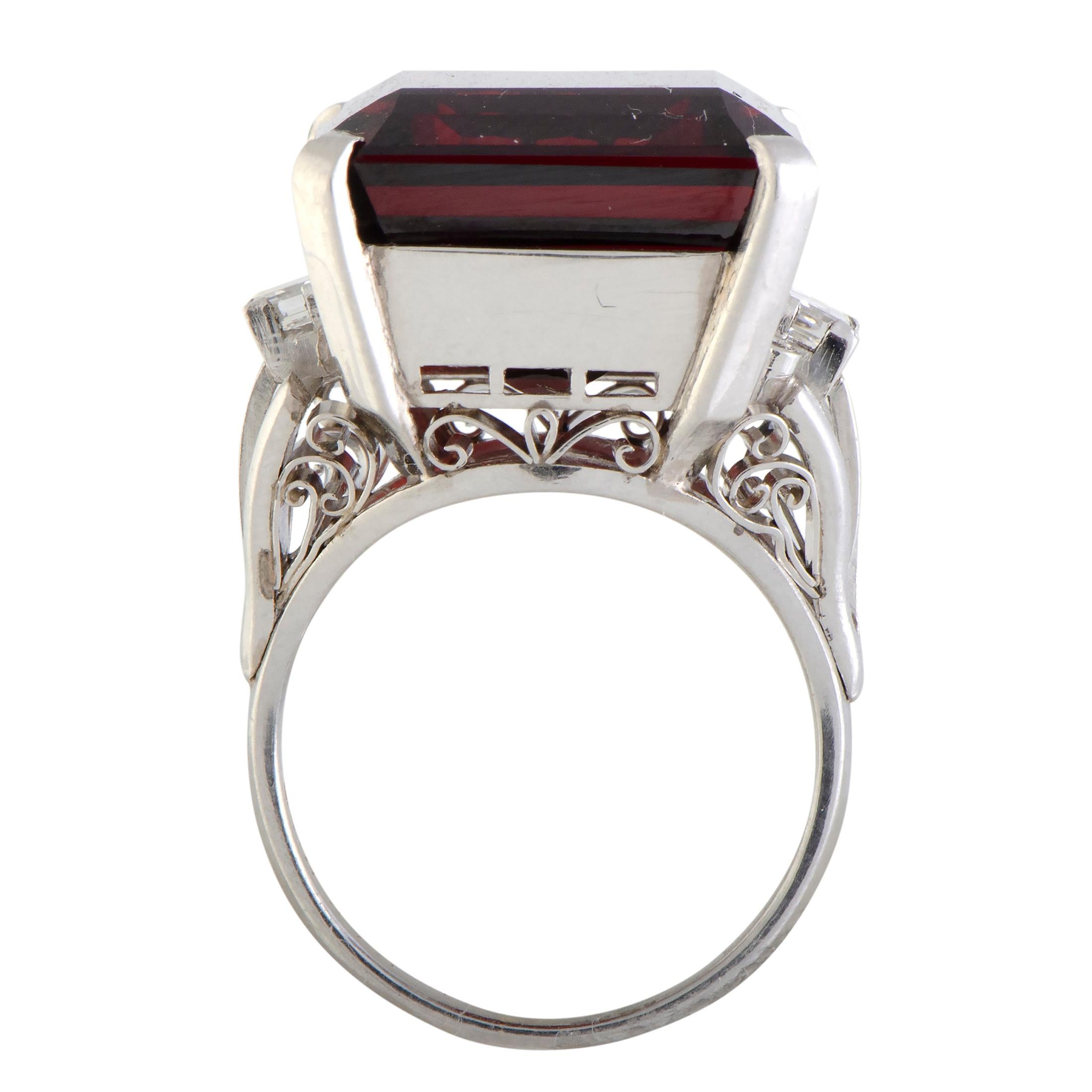 A stunningly regal look is created in this majestic ring by presenting an exceptionally refined design in prestigious platinum and using it as a sublime pedestal for an expertly cut garnet. The garnet weighs approximately 16.00 carats and it is