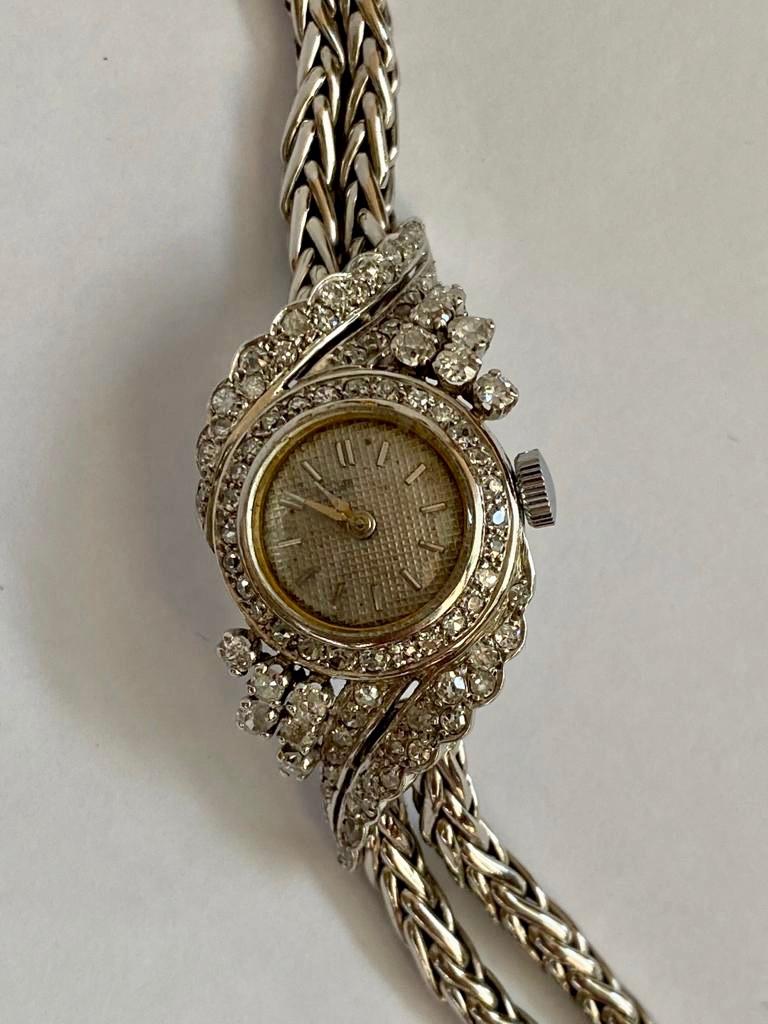This elegant diamonds and platinum bracelet watch is a beautiful object to have when going out. It has an automatic winding. Grey gold 18k and platinum. The circular dial of the watch is crimped with 28 small diamonds, size 8/8. The foliage decor is