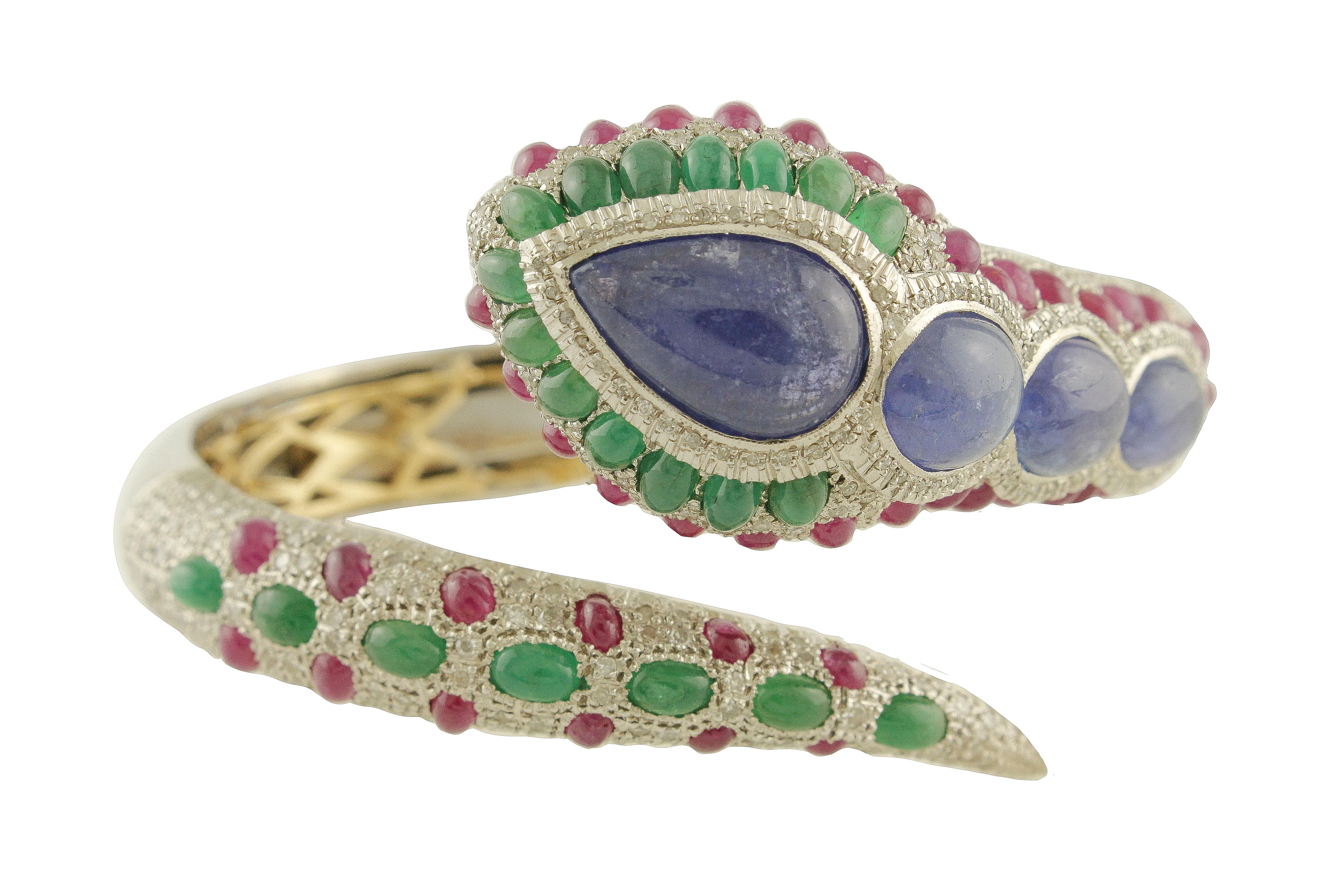 Elegant snake shape bracelet in 9K rose and white gold and silver structure mounted with 3 oval shape tanzanite on the neck and one tanzanite drop (1.6 cm X 1 cm) on the head, aroud it there is emeralds row and an other ruby row that finish on the