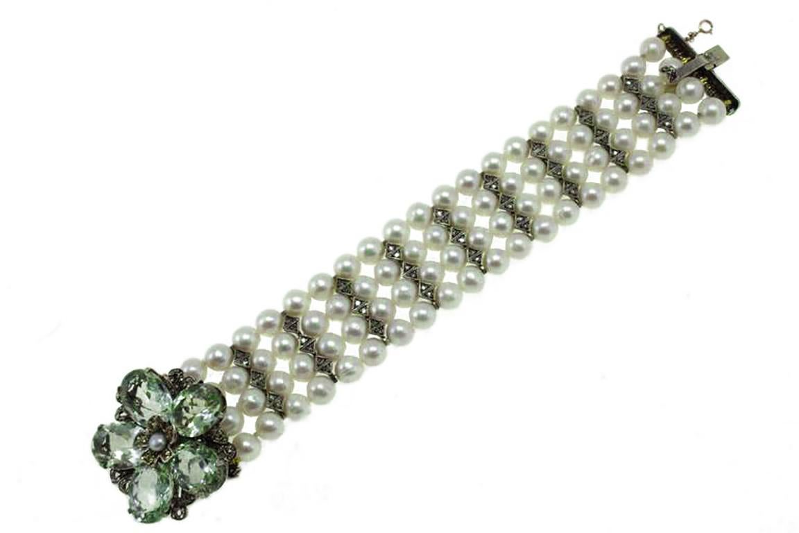 Beaded bracelet in 9kt gold and silver composed of 4 pearls rows and flower shaped clasp mounted with diamonds, green amethyst as petals, topaz and one pearl in the center. 
Diamonds 1.14 kt
Yellow sapphires 0.37 kt
Green Amethyst 9.10 gr
Pearls