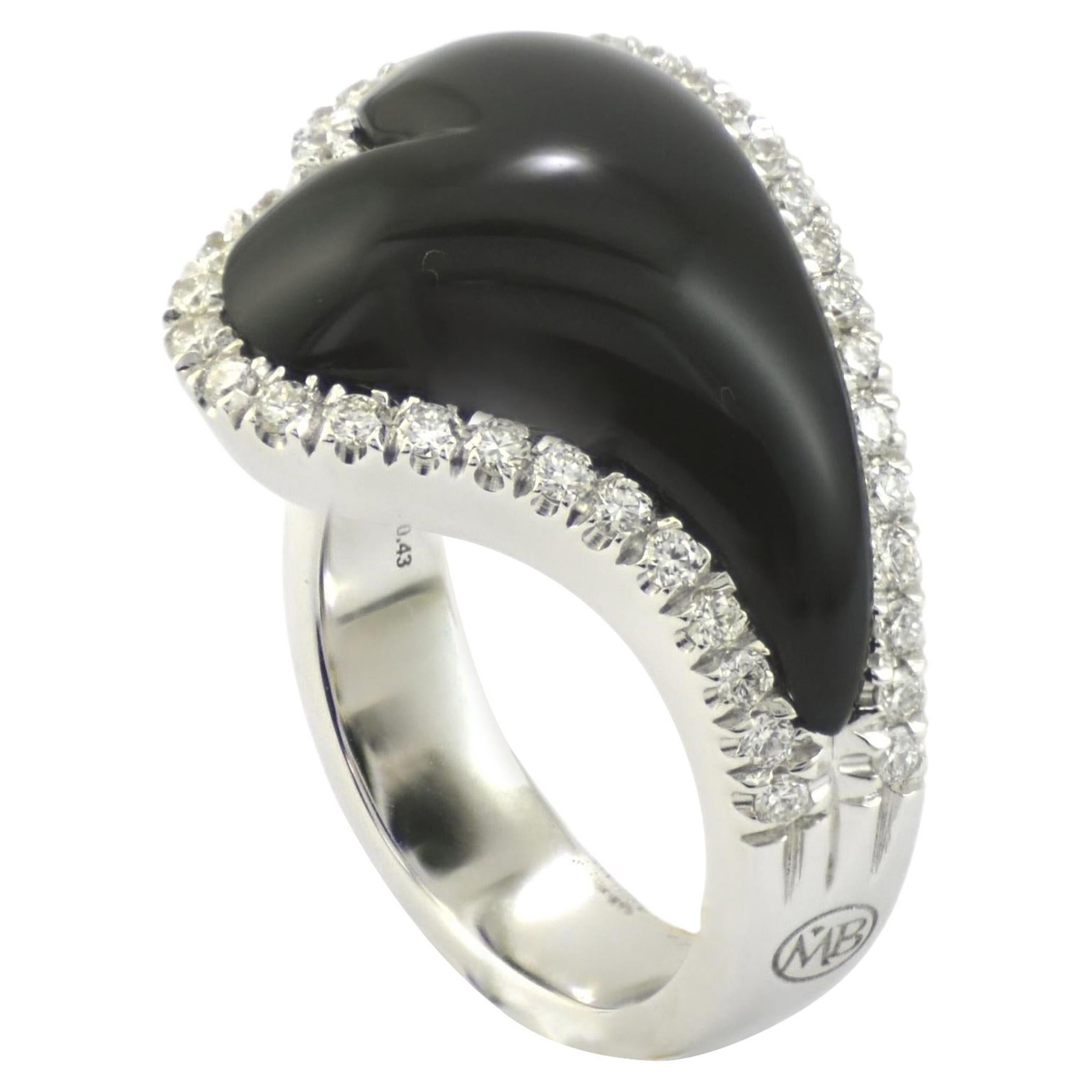 Handcrafted in Italy in Margherita Burgener family workshop, the ring is designed a stylized heart shape. 
Centering  a bombé carved onyx, surrounded by a line of diamonds.
Inside the ring you an appreciate open worked heart shaped