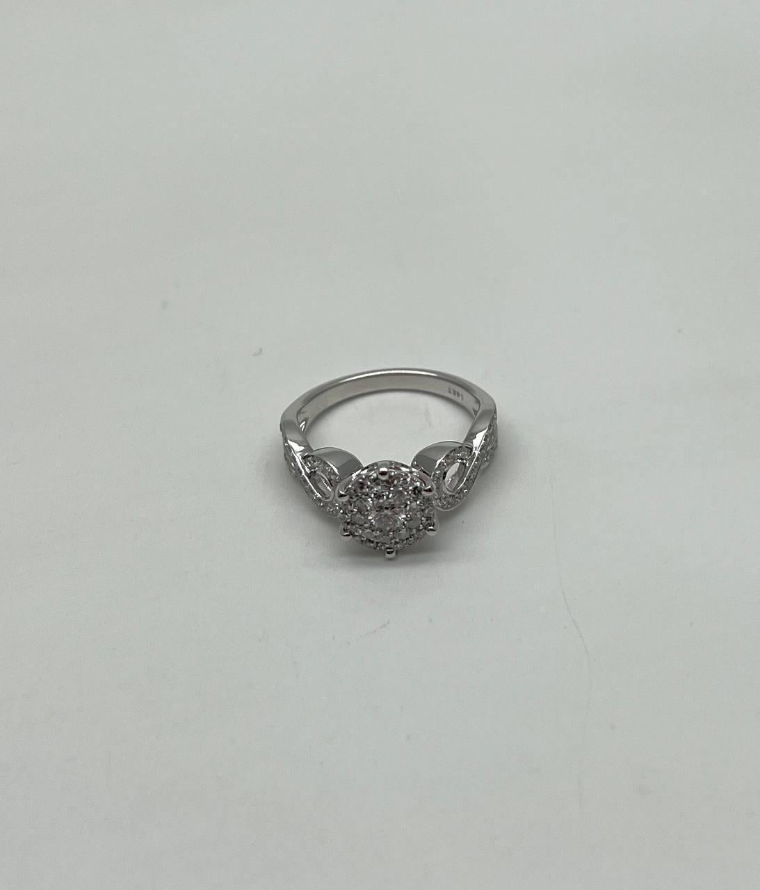 Questo squisito anello è realizzato in oro bianco 14k. Il centro è caratterizzato da uno splendido diamante a taglio rotondo, del peso di 0,75 carati, incastonato in una sofisticata montatura. Il design include dettagli intricati lungo la fascia,