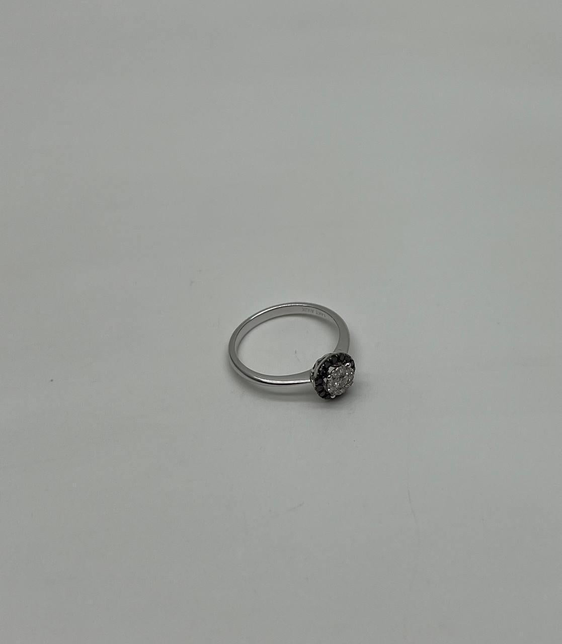 This elegant ring is crafted in 14K white gold. It features a central round diamond weighing approximately 0.33 carats, surrounded by a halo of black diamonds. The primary diamond is set in a sleek, modern design.