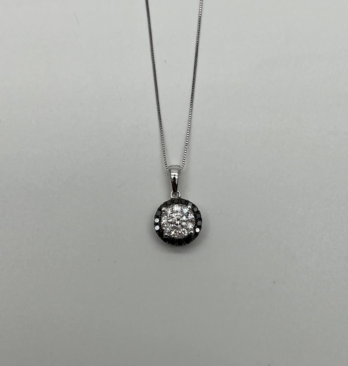 Una straordinaria collana con ciondolo di diamanti. Presenta un gruppo centrale di diamanti tondi brillanti, circondati da un'aureola di diamanti neri che creano un contrasto accattivante. La pietra principale pesa 0,5 carati ed è incastonata in un