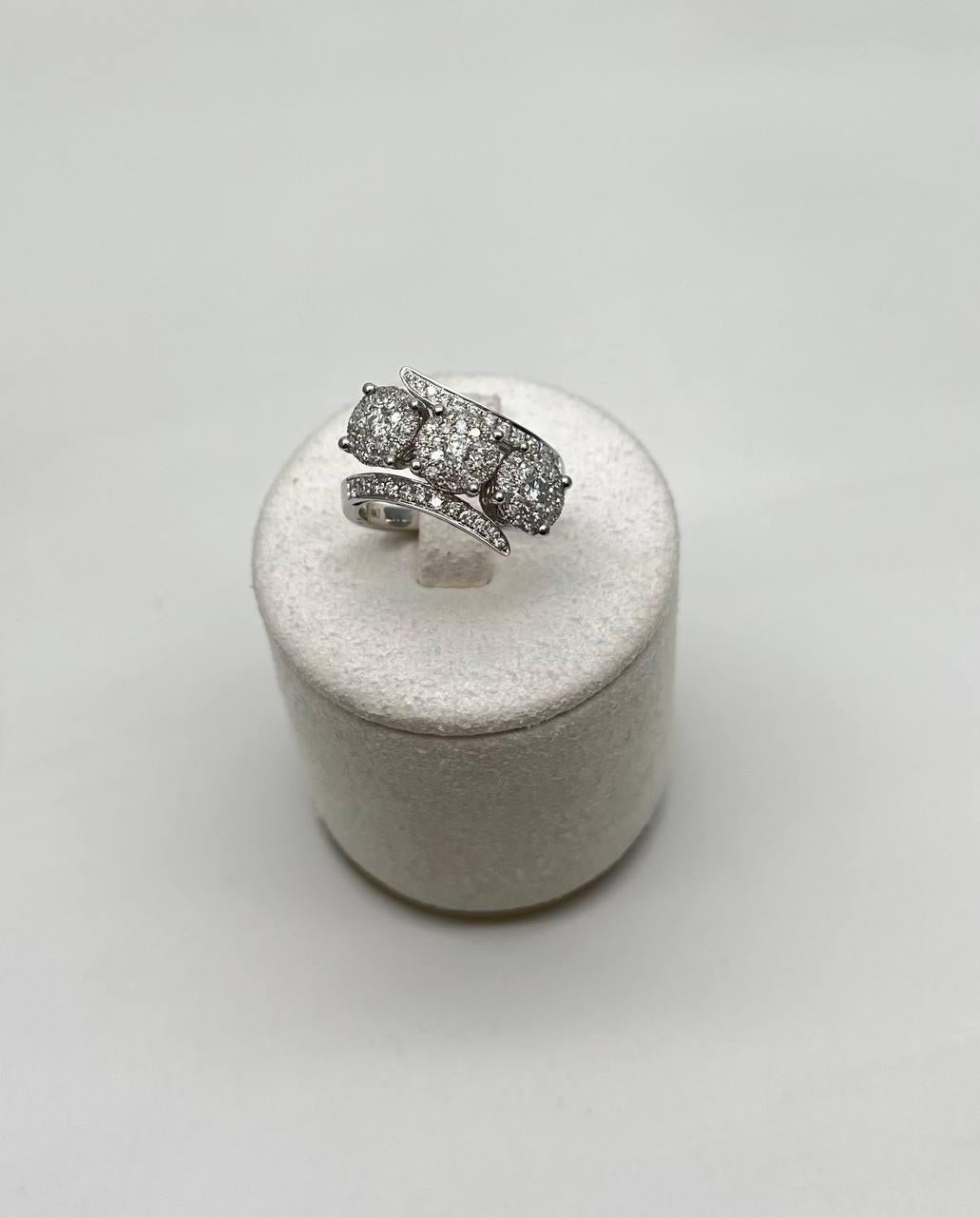 Cette bague exquise présente un design moderne avec trois grappes de diamants ronds étincelants (1,0 CtW). Les grappes sont élégamment encadrées par des bandes d'or blanc 14K élancées et incurvées, incrustées de diamants plus petits, créant ainsi