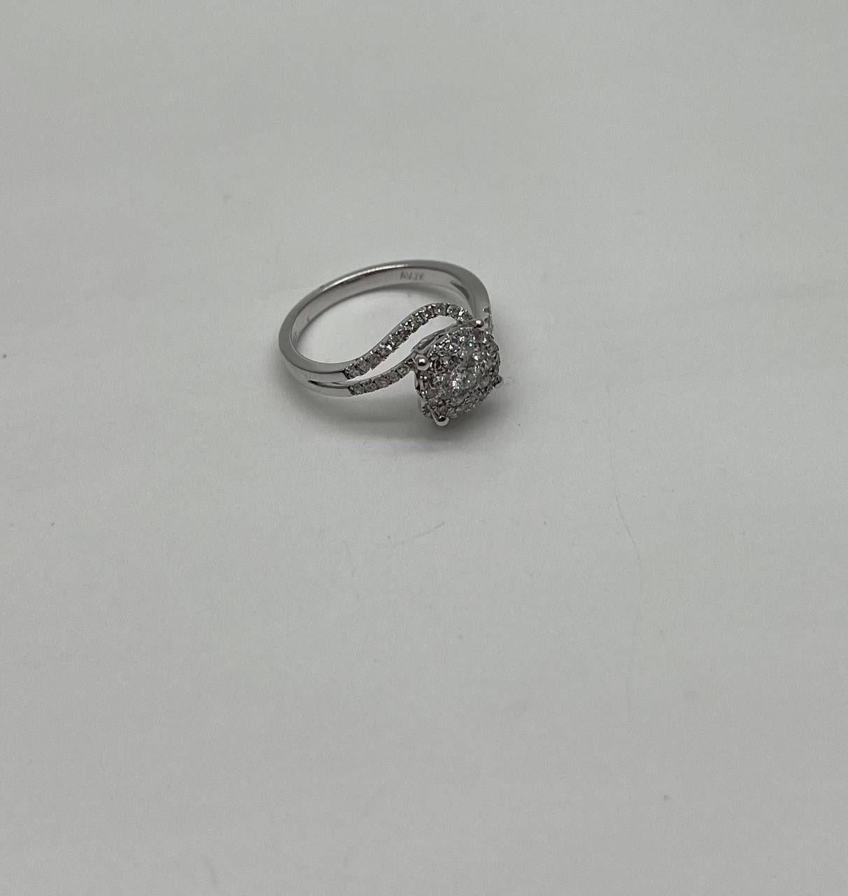 Eine Sinfonie aus Kurven, Glanz und Eleganz. Dieser auffällige Ring ist mit 0,65 Karat runden weißen Diamanten besetzt. Der zentrale Stein ist von einem Wirbel kleinerer Diamanten umgeben, die alle in glänzendes 14-karätiges Weißgold gefasst sind.