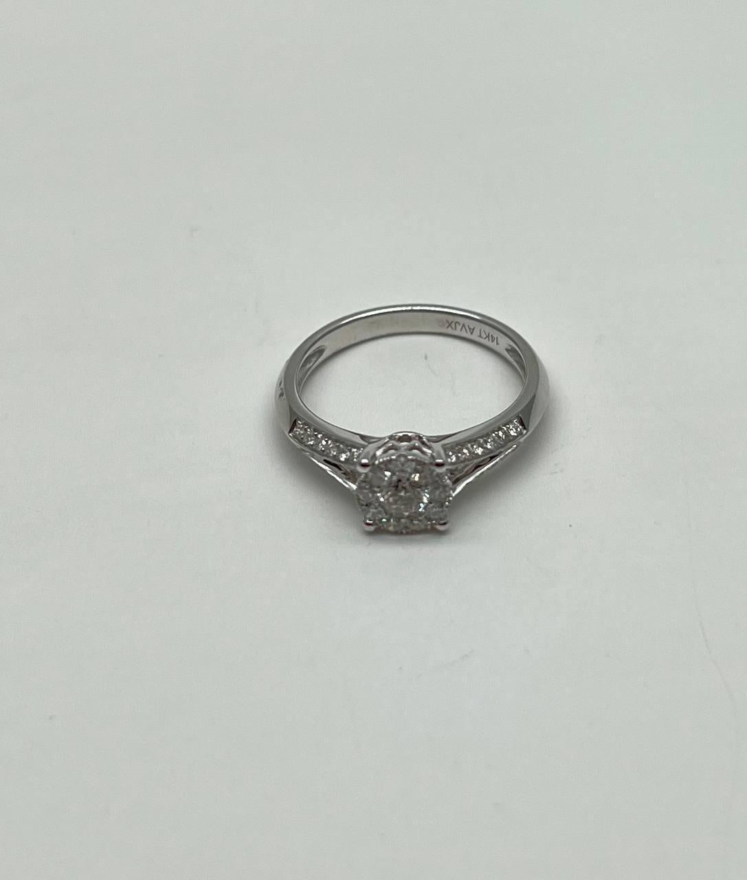 Questo elegante anello è realizzato in oro bianco 14K. Presenta un diamante bianco rotondo brillante (colore G) del peso di circa 0,5 carati. La fascia è ornata da altri diamanti più piccoli che ne esaltano lo splendore.