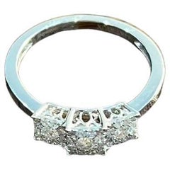 Anillo de tres piedras en oro blanco con diamantes engastados con pavé en racimo cuadrado y halo
