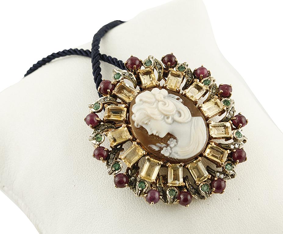 Gorgeous Brooch/ Pendant necklace in 9K rose gold and silver structure composed of a refine carved cameo in the center, yellow topazes crown, rubies crown and leaved detailes around studded by diamonds and emeralds.
Diamonds 0.20 ct 
Rubies and