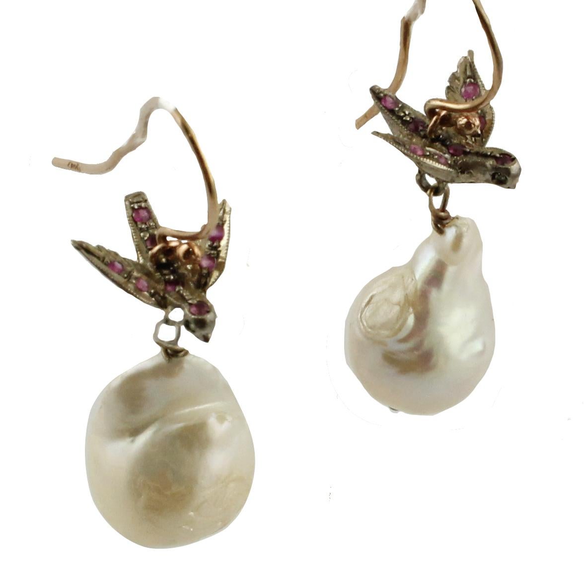 Dangle earrings in 9K rose gold and silver structure composed of birds studded by little rubies on the body and diamonds like eyes at the top, at the bottom there are two white irregular pearls.
Diamonds 0.01 ct 
Rubies 0.64 ct 
Pearls 7.10 g    1.9