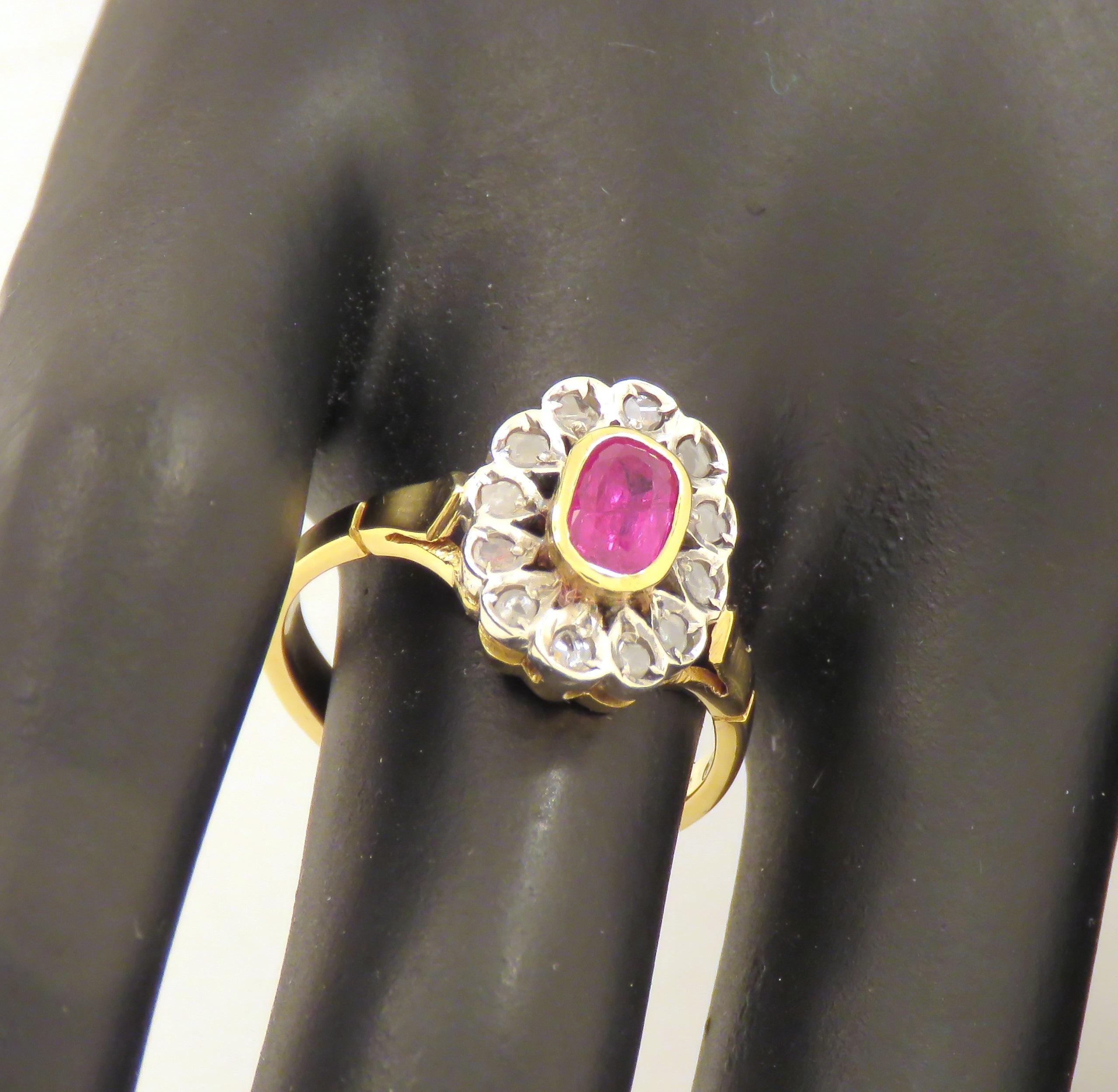 Beautiful vintage ring handcrafted in silver and 18 karat yellow gold featuring a bejeweled flower made of an oval cut ruby 1.00 ctw circa surrounded by 12 rose cut diamonds. The dimension of the ruby is: 7x4 mm 0.275x0.157 inches. US finger size is