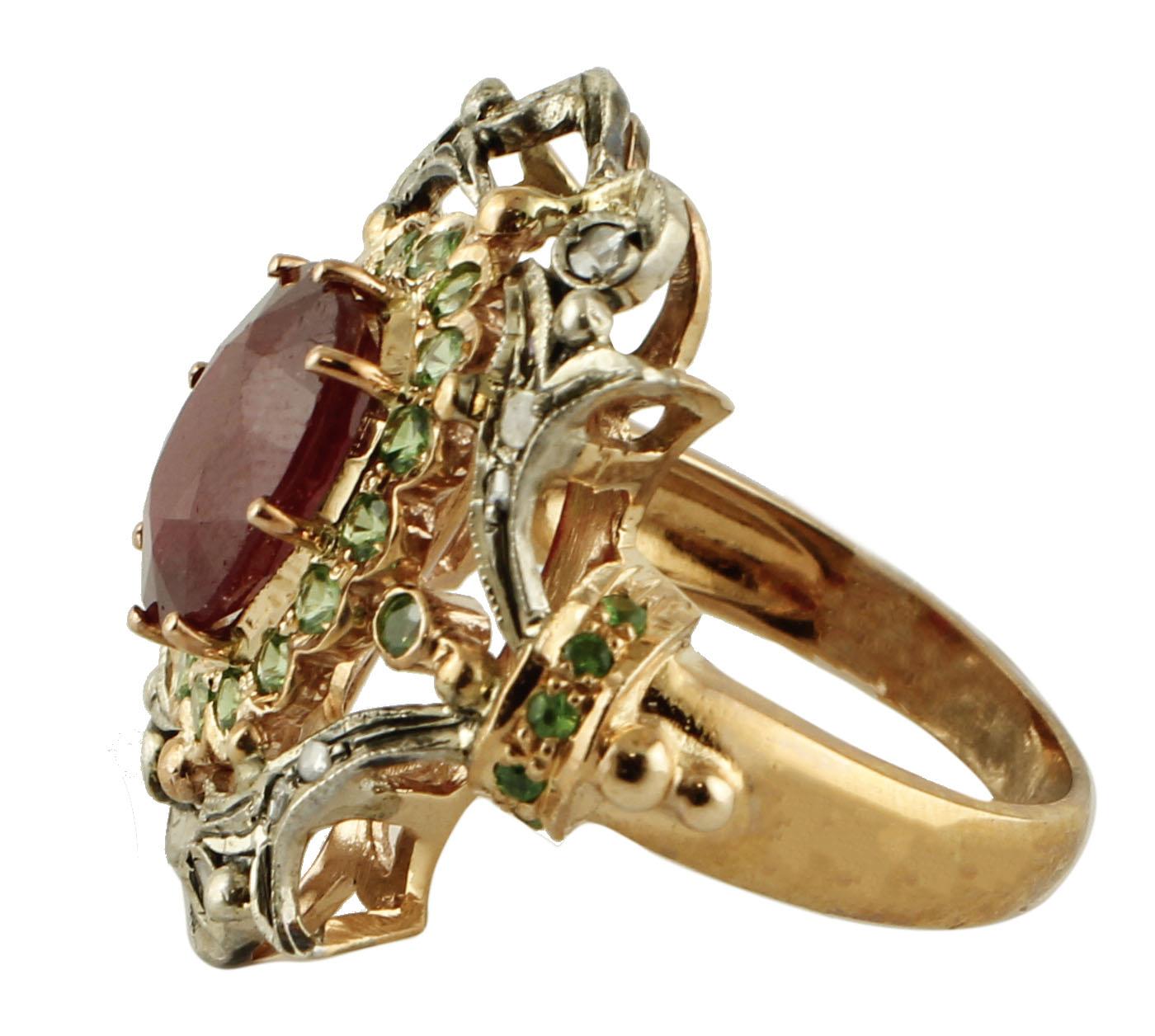 Wonderful retro ring in 9k rose gold and silver structure, mounted with a central intense ruby surrounded by a rose gold crown studded with tsavorite and silver details studded with diamonds all around.
The origin of this ring goes back to 1960s. It
