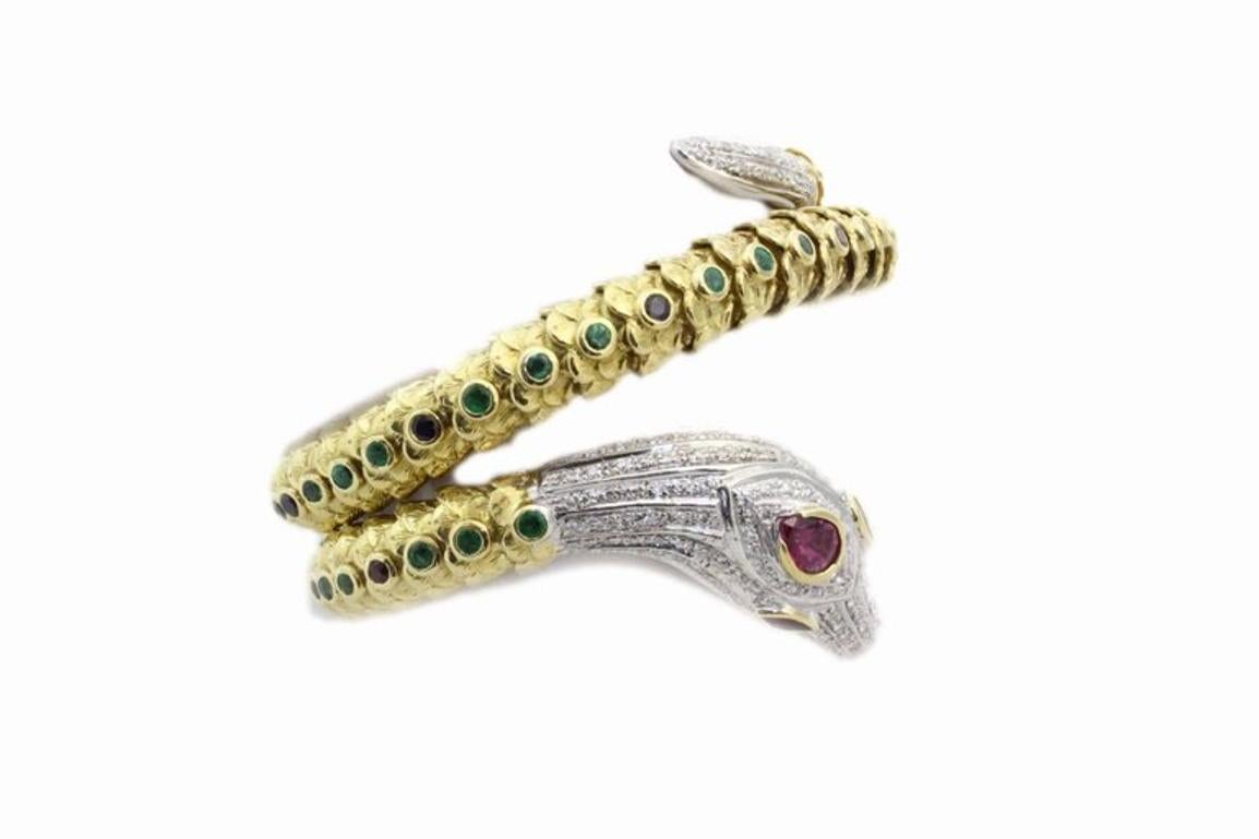 Shapely bracelet settled in 18 Kt yellow gold and 18 Kt white gold, with a snake shape. The snake body is embellished with blue sapphires and emeralds, the snake's head is mounted din  18 Kt white gold embellished of diamonds and rubies.
Tot weight