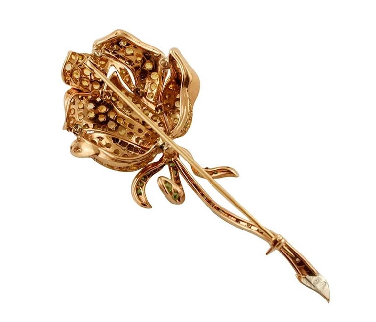 Vintage brooch in 14k rose gold and silver structure, designed as an elegant flower studded with diamonds, yellow sapphires and tsavorite.
The origin of this brooch goes back to the 1970s, it was totally handmade by Italian master goldsmiths and it