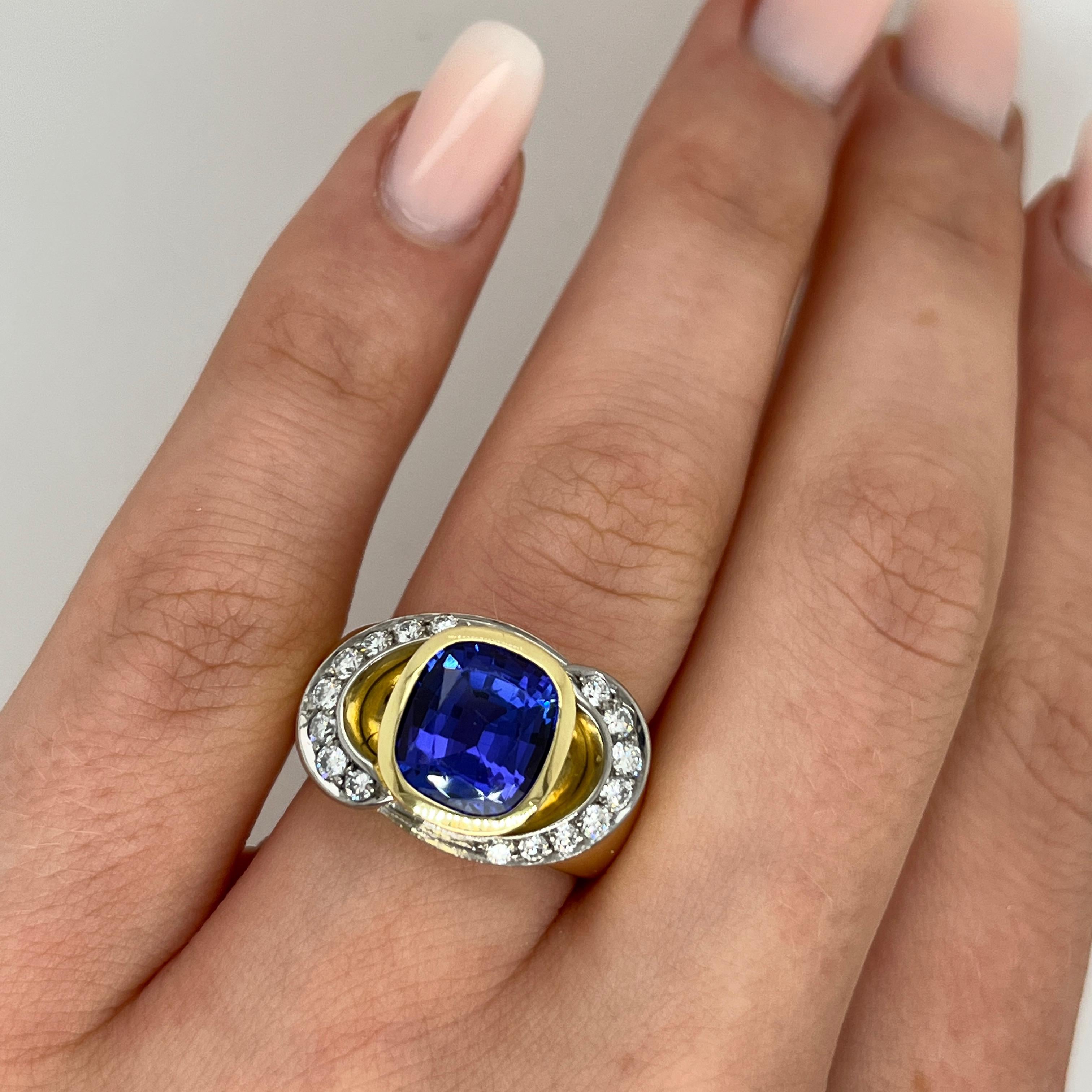 Ein eleganter und auffälliger Clusterring, gefertigt aus einer harmonischen Mischung aus 18 Karat Gelb- und Weißgold. In seinem Zentrum liegt ein farbenprächtiger, kissenförmiger Tansanit, der eine tief violettblaue Brillanz ausstrahlt. Der