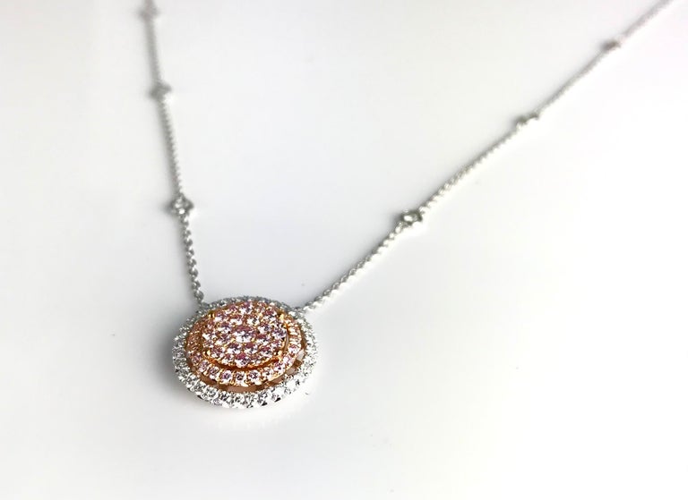This beautiful pendant features multiple round pink diamonds arranged in a cushion shape, inside a halo of round white diamonds. Additional diamonds decorate the 18