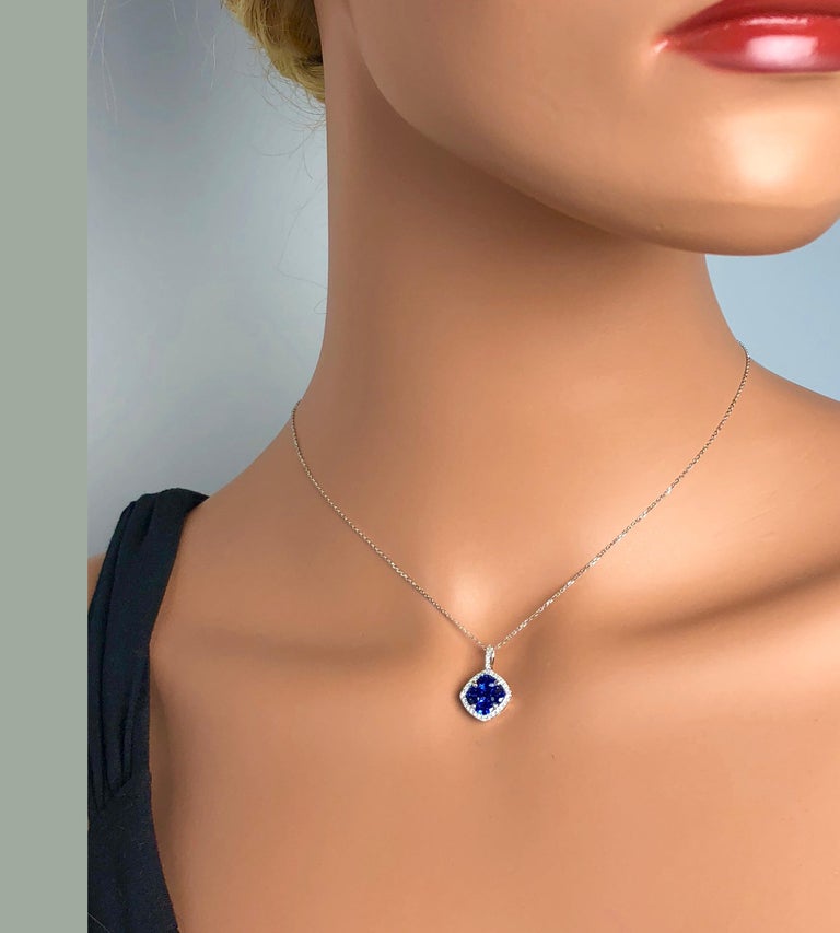This pendant features a rounded square cluster of four oval cut and one princess cut vivid blue sapphires (total weight 1.09 carats), surrounded by a halo of round white diamonds, which also extend up the bail (total diamond weight 0.13