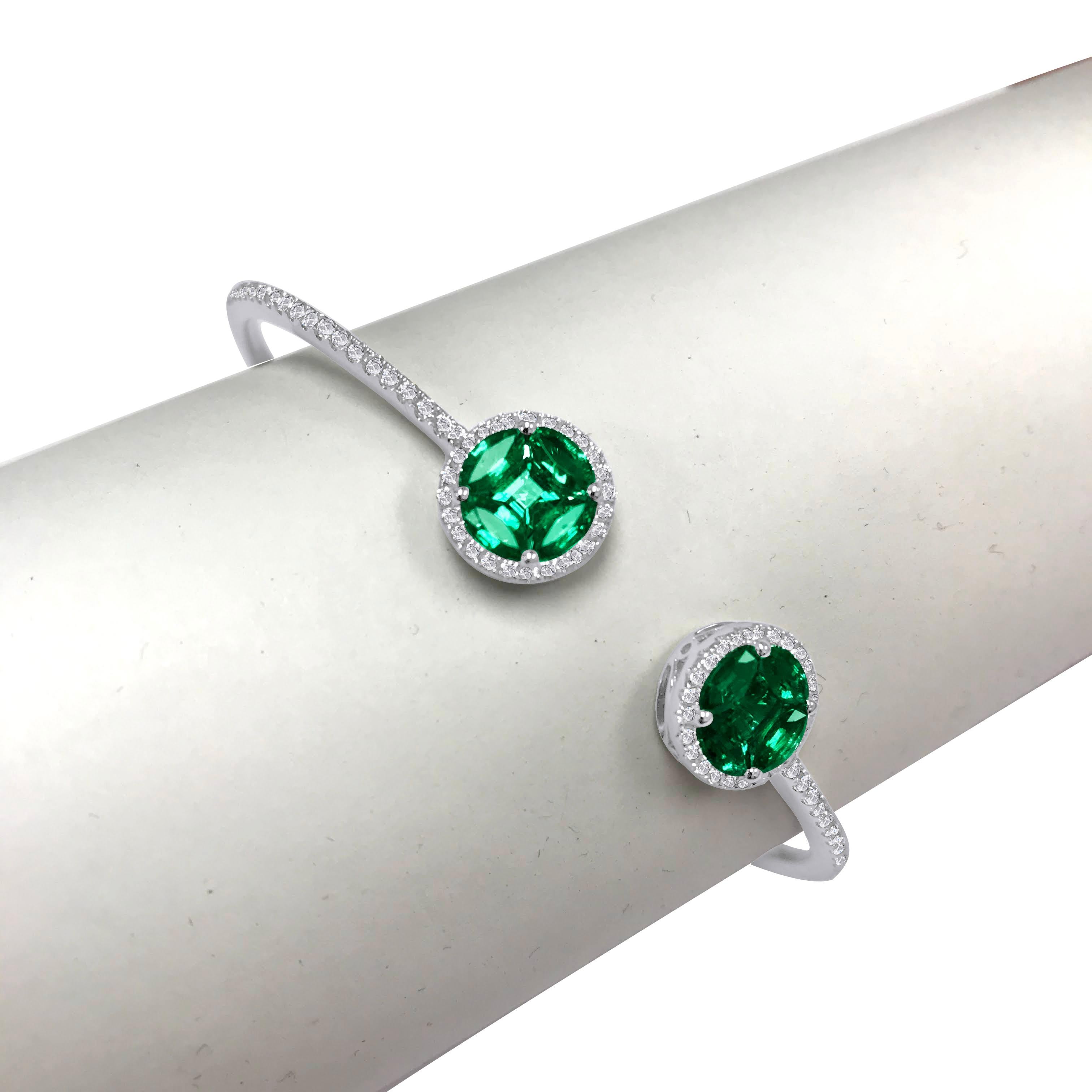 The heads on this bangle are formed by two clusters of 10 emeralds. Each head is a round illusion formed by four marquise cut and one square cut emerald. Each cluster is wrapped in a tight halo of round white diamonds, which also extends to the