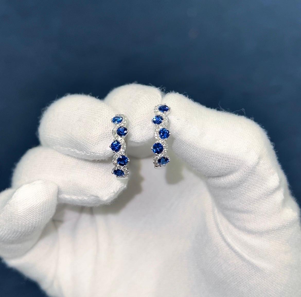 (DiamondTown) These lovely earrings each feature five round cut vivid blue sapphires (total weight 1.65 carats) inside a weaving curve of round white diamonds (diamond weight 0.33 carats).

The earrings close by lever-back and are set in 18k White
