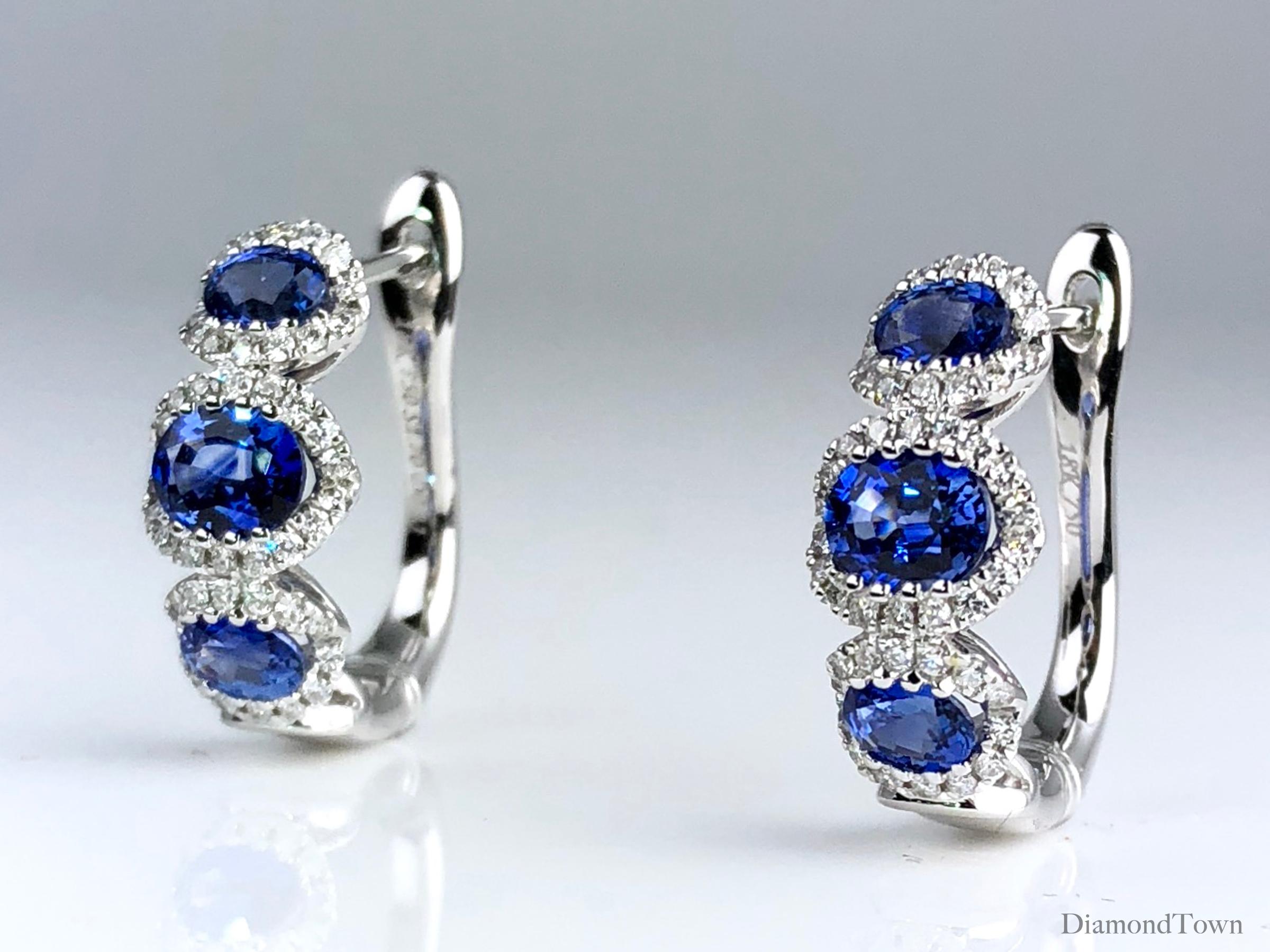 (DiamondTown) These gorgeous Diamond Town earrings feature three vivid blue oval cut sapphires (1.70 carats total), each inside a halo of round white diamonds (0.31 carats total). The earrings close securely by lever-back and are set in 18k White