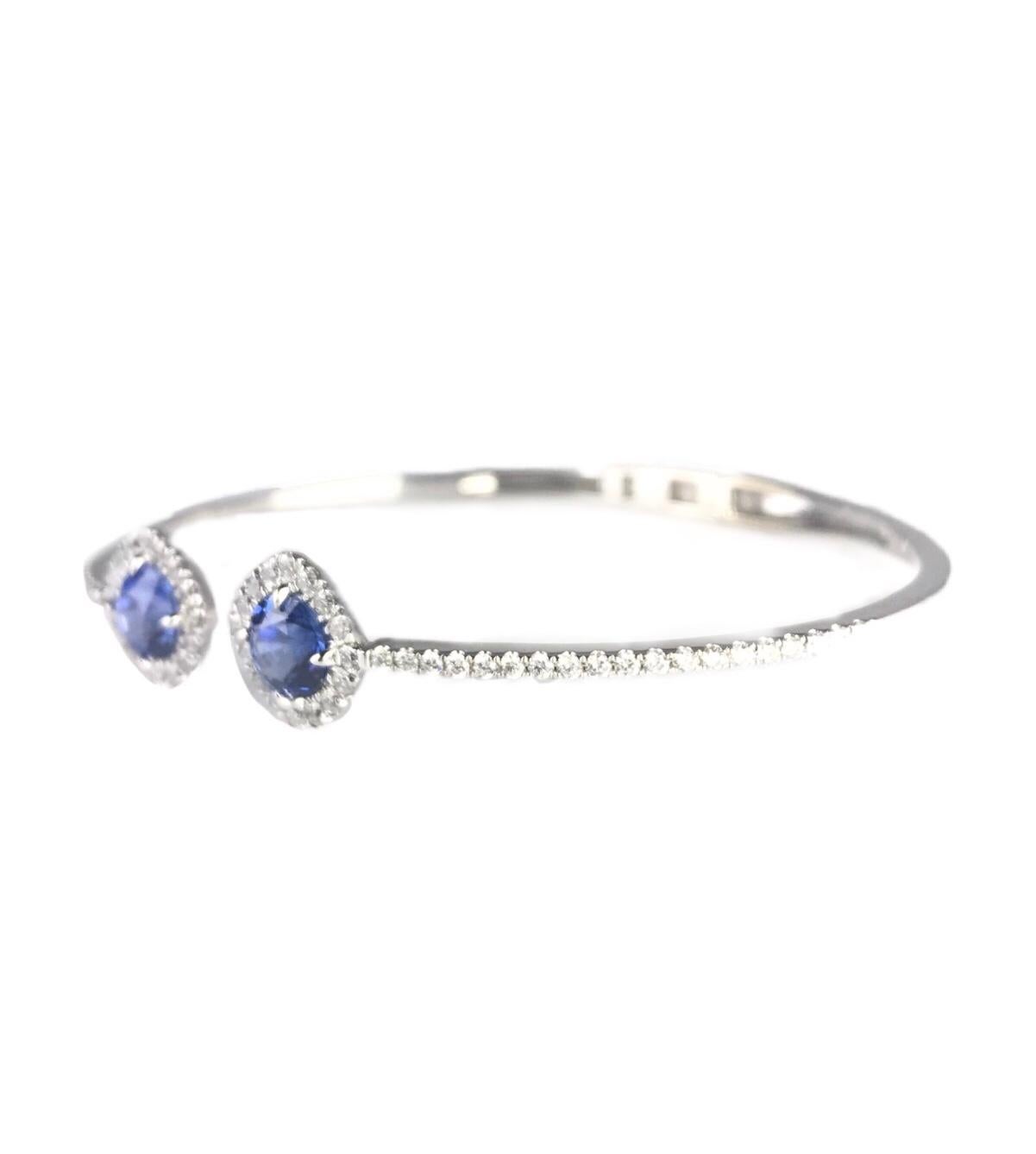 This bangle bracelet has two round sapphires totaling 2.23 carats at the heads. Each sapphire is inside a halo of round diamonds, with additional diamonds extending halfway down the length of the bangle (total weight 0.86 carats).
Set in 14k White
