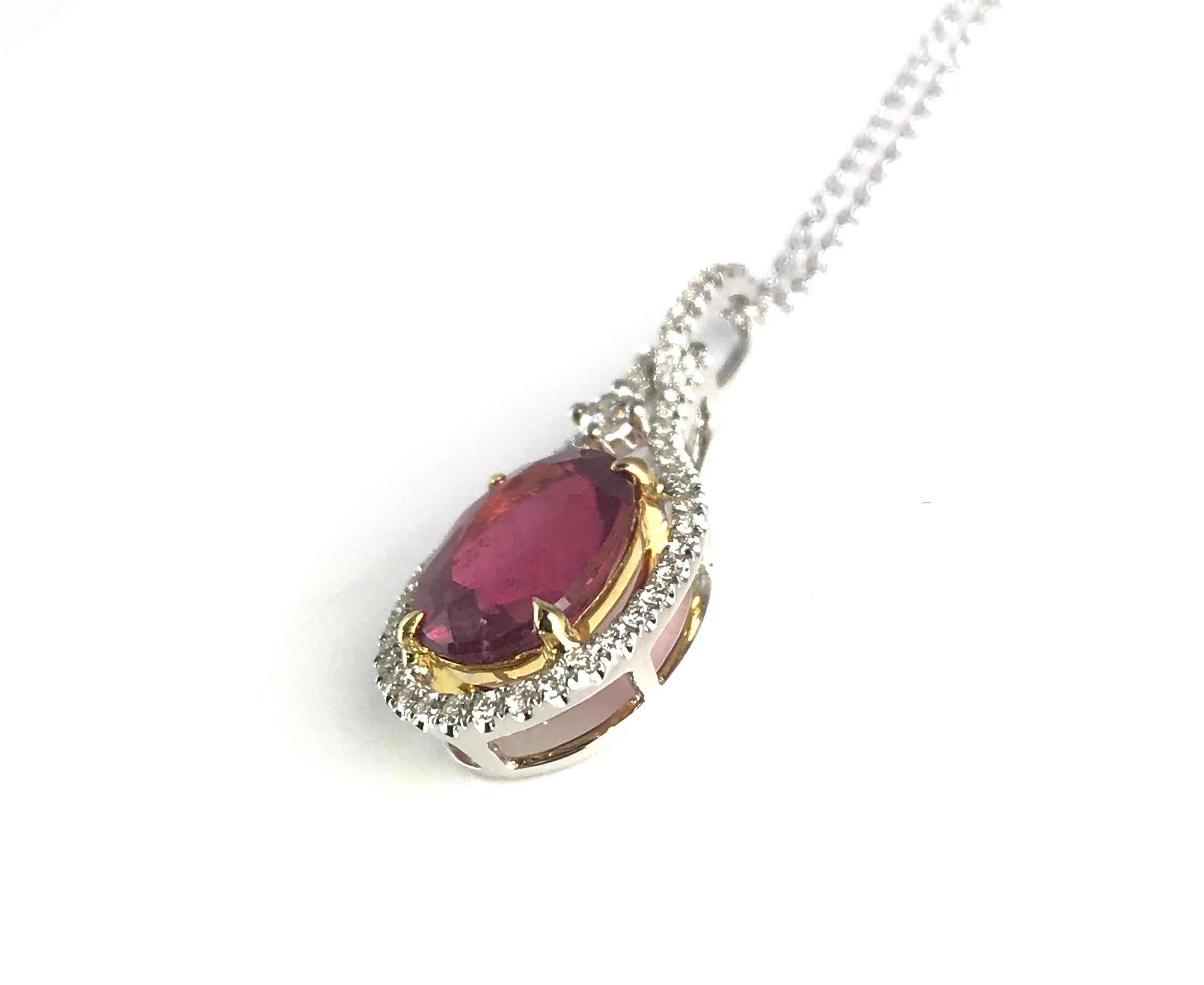 Within this exquisite pendant, you'll find a 2.60 carat oval-cut raspberry tourmaline gracefully encircled by round white diamonds. The tourmaline is delicately nestled in an 18k yellow gold setting, while the remainder of the piece is elegantly