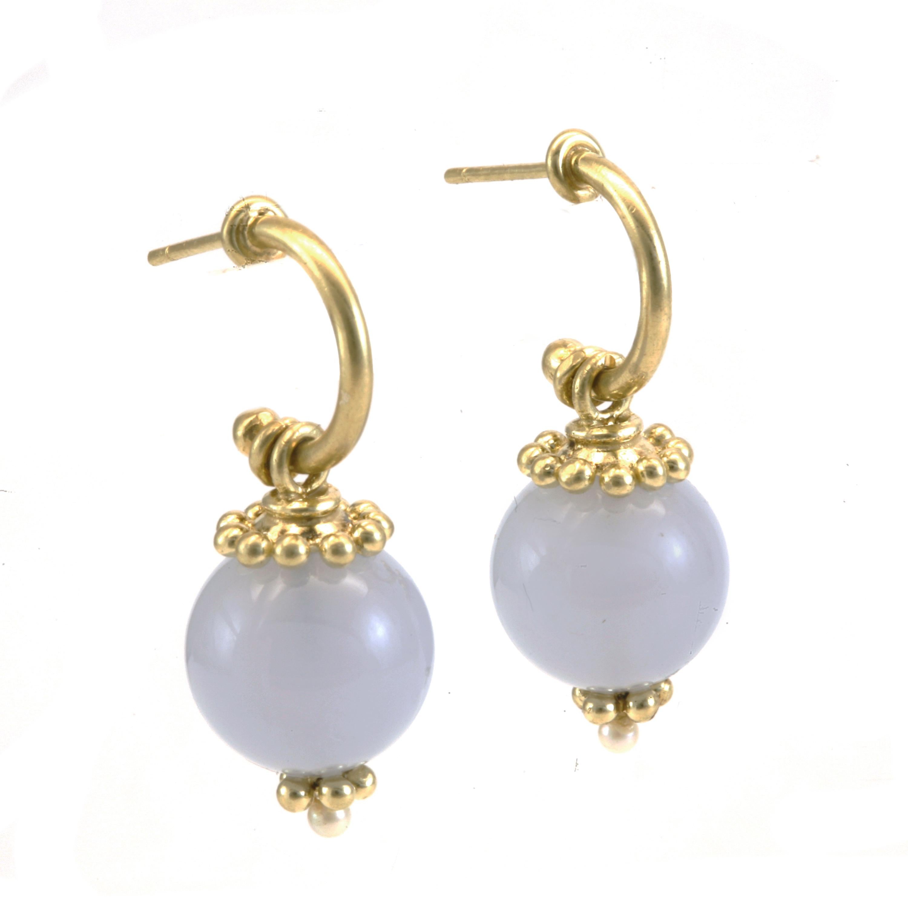 Blue Chalcedony Drop Hoop Earrings in 18k Gold measure 1 1/4 inches. Blue Chalcedony is a gem that flatters any complexion. From the fairest to the deepest complexion. These voluminous beads are suspended with hand fabricated caps and a finial that