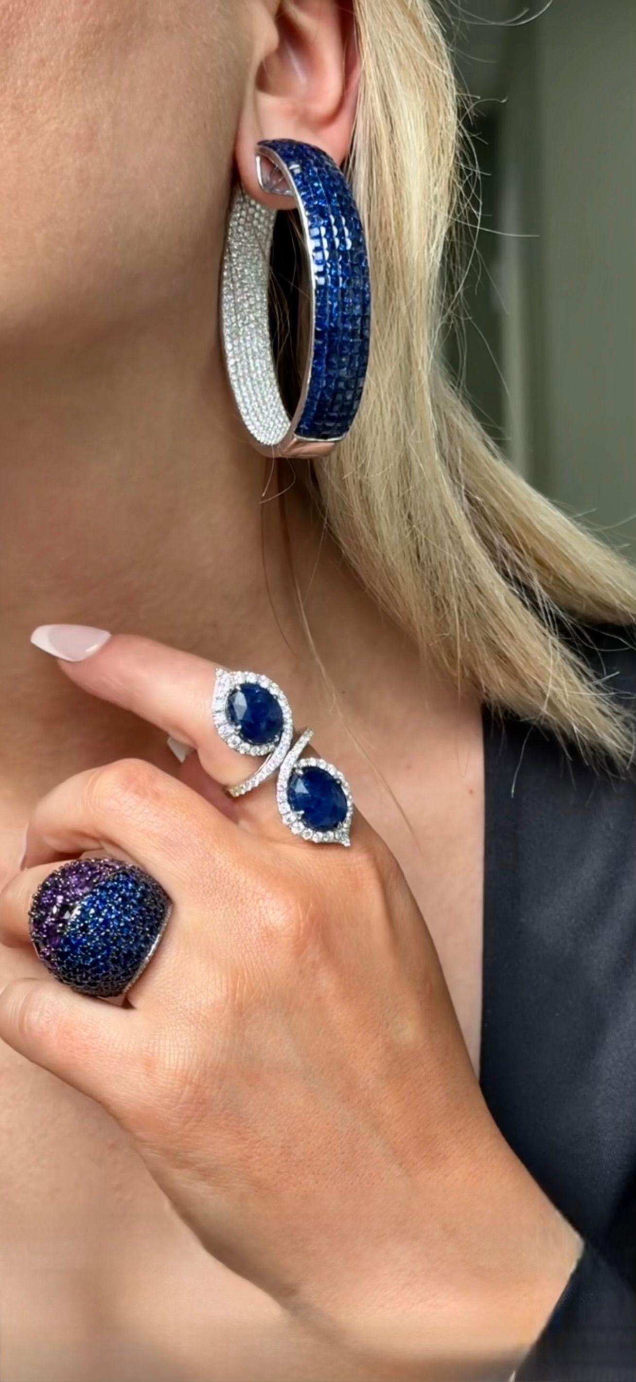 Der Ring mit zwei Steinen enthält einen seltenen ovalen burmesischen blauen Saphir im Rosenschliff von 15,30 Karat, der von 1,95 Karat runden Diamanten akzentuiert wird, alle in 18 Karat Weißgold gefasst. 
Diana M. ist seit über 35 Jahren ein