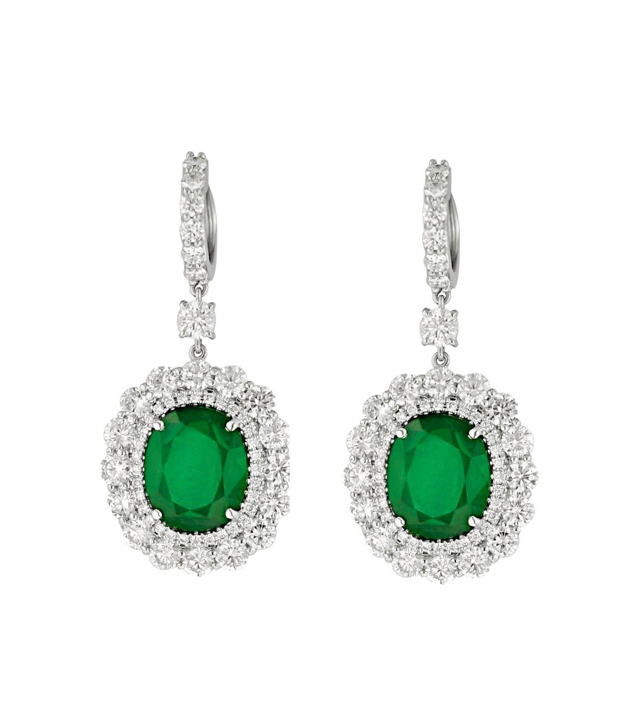 18 kt white gold emerald earrings featuring center 9.21 cts tw GIA certified green oval shaped emeralds surrounded by 6.00 cts tw of round diamonds set all the way around 