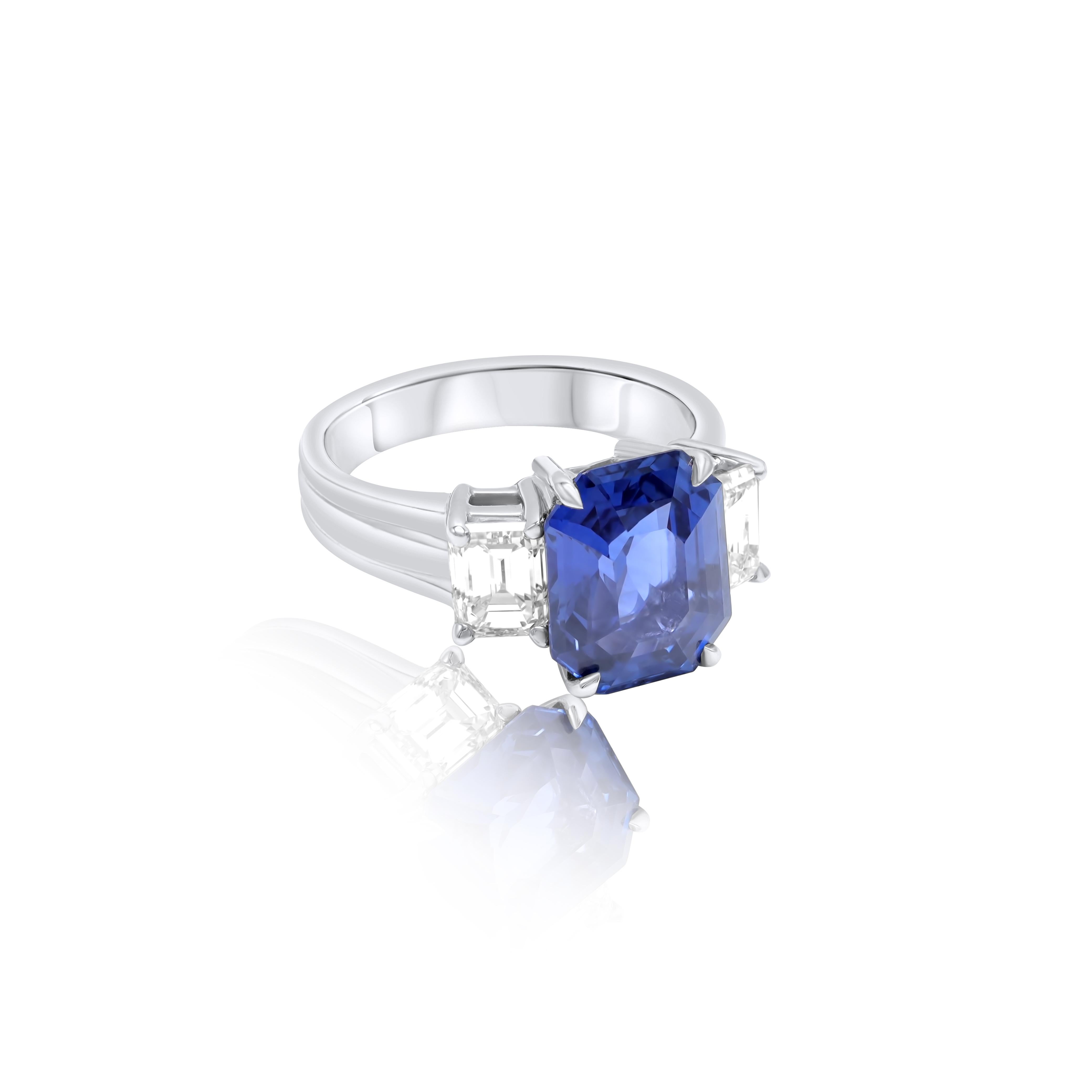Platinum sapphire and diamond ring featuring a 6.04 ct natural emerald cut Ceylon sapphire with 2 emerald cut diamonds on each side totaling 1.50 cts of diamonds 