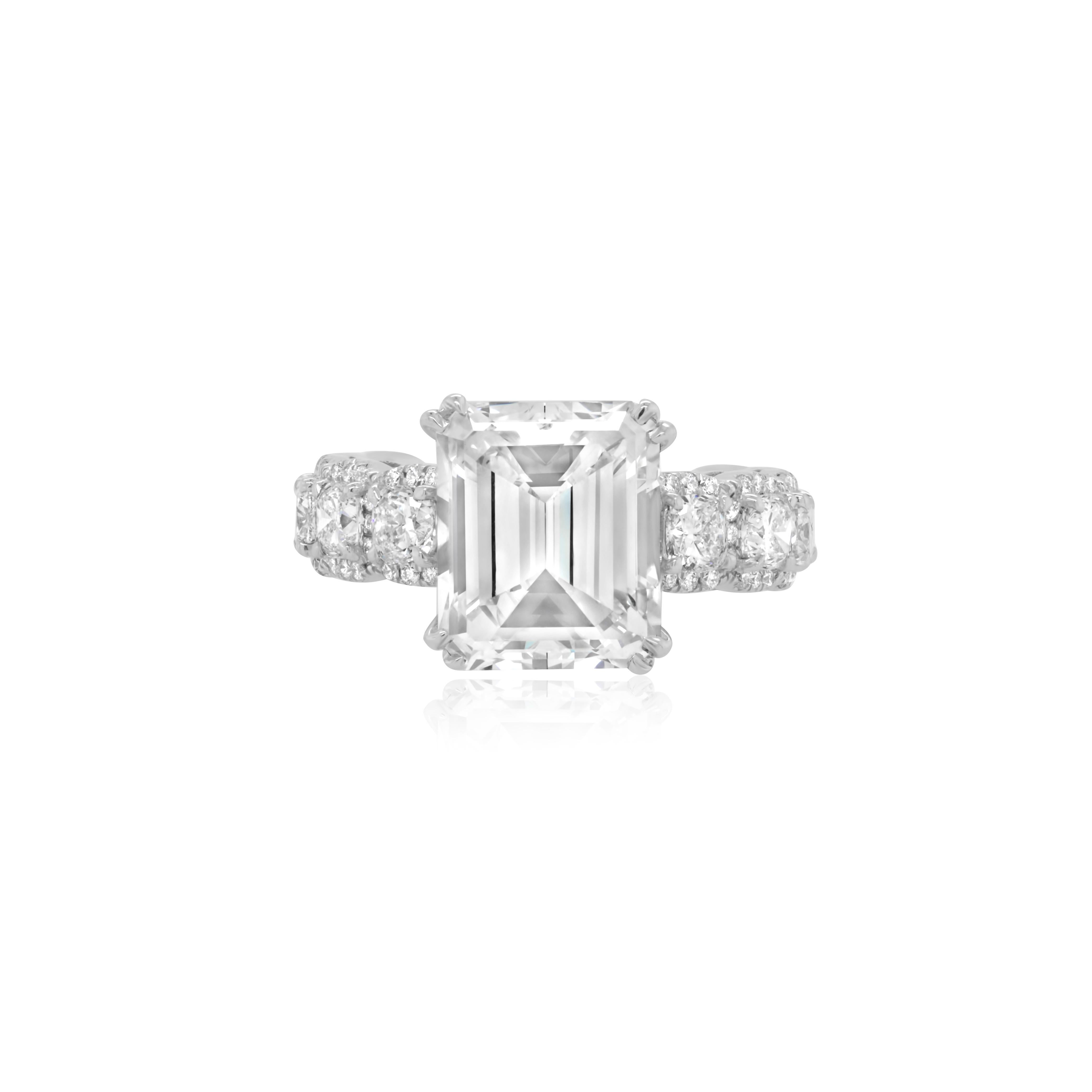 Crafted in luxurious platinum, this enchanting engagement ring showcases a magnificent 5.04 carat emerald cut diamond at its center, graded as J color and SI1 clarity. The mesmerizing diamond is securely set within a sleek and sophisticated mounting