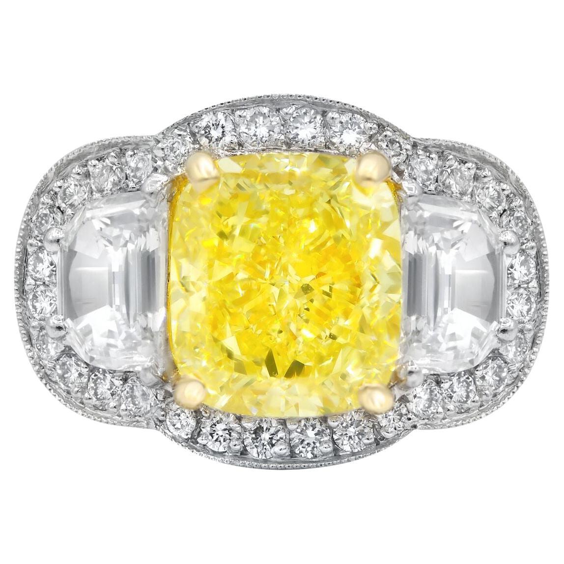 Platinum and 18 kt yellow gold diamond ring featuring a center (FY VS1) 5.23 ct cushion cut yellow diamond with 2 half moon shaped diamonds on the sides and surrounded by 1.90 cts tw of white diamonds 

Diana M is one-stop shop for all your jewelry