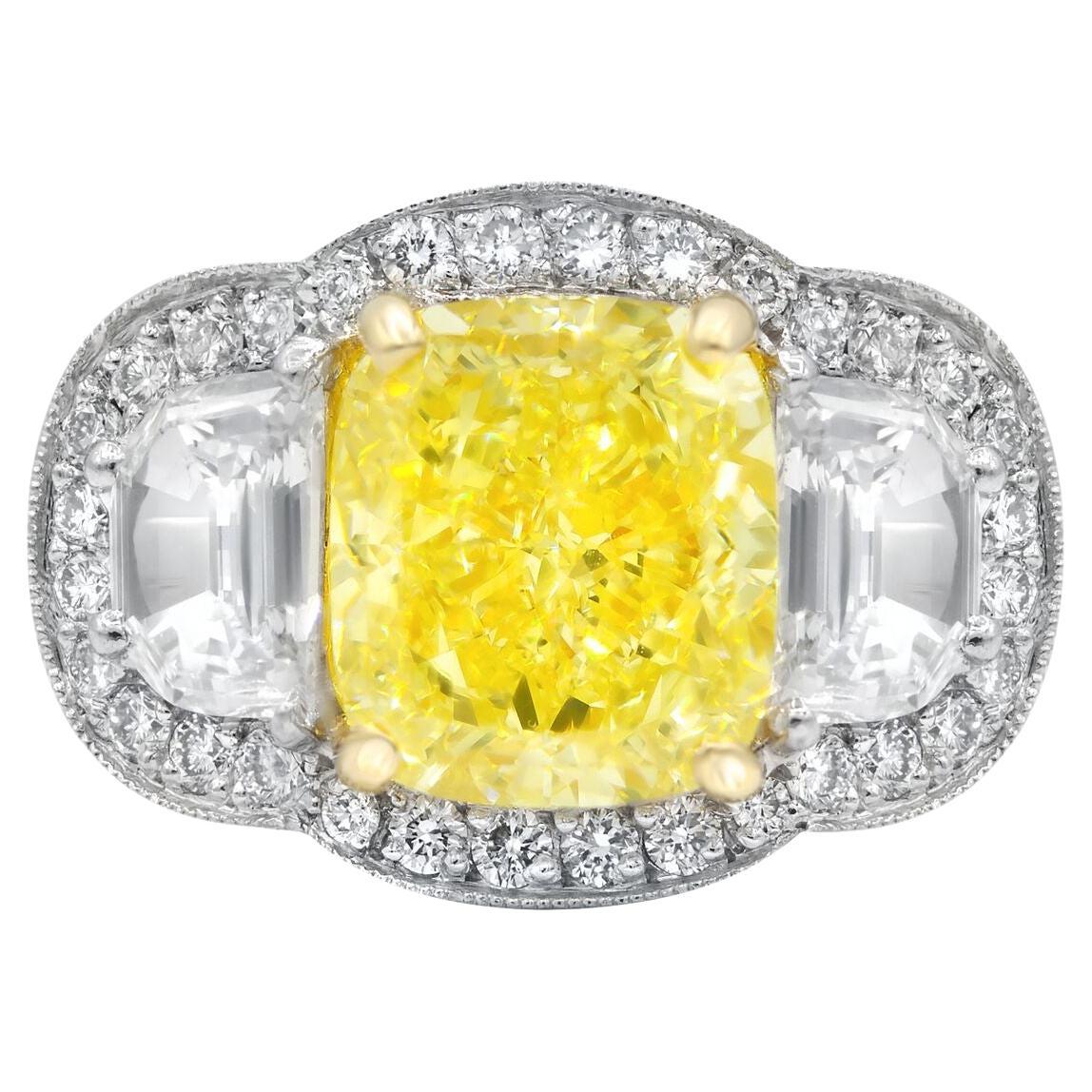Platinum and 18 kt yellow gold diamond ring featuring a center (FY VS1) 5.23 ct cushion cut yellow diamond with 2 half moon shaped diamonds on the sides and surrounded by 1.90 cts tw of white diamonds 

Diana M is one-stop shop for all your jewelry