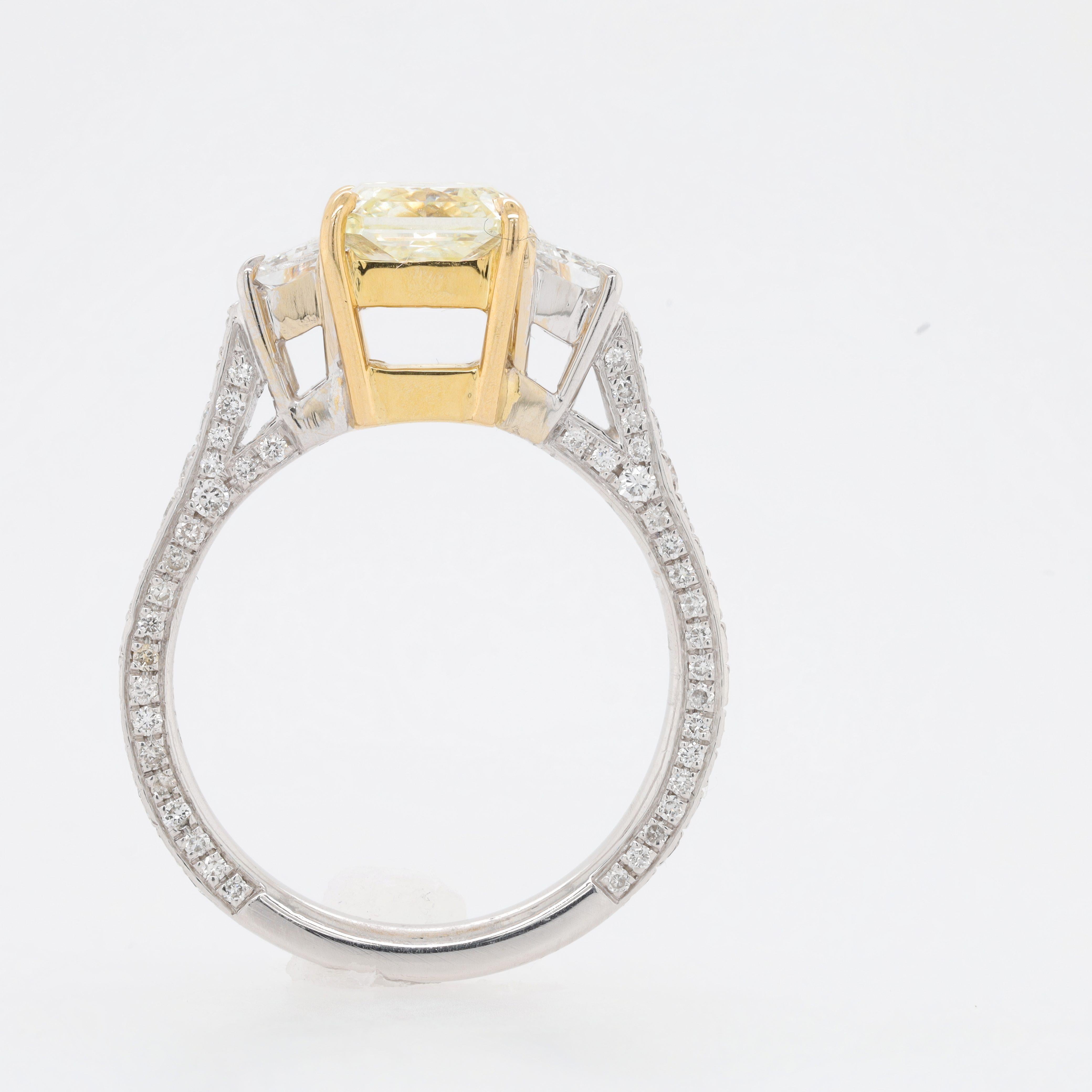 Platinum and 18 kt yellow gold engagement ring featuring a center (FY VVS2) 1.78 ct radiant cut diamond with 2 trapezoid shaped diamonds on the sides and round diamonds going around the band totaling 1.15 cts