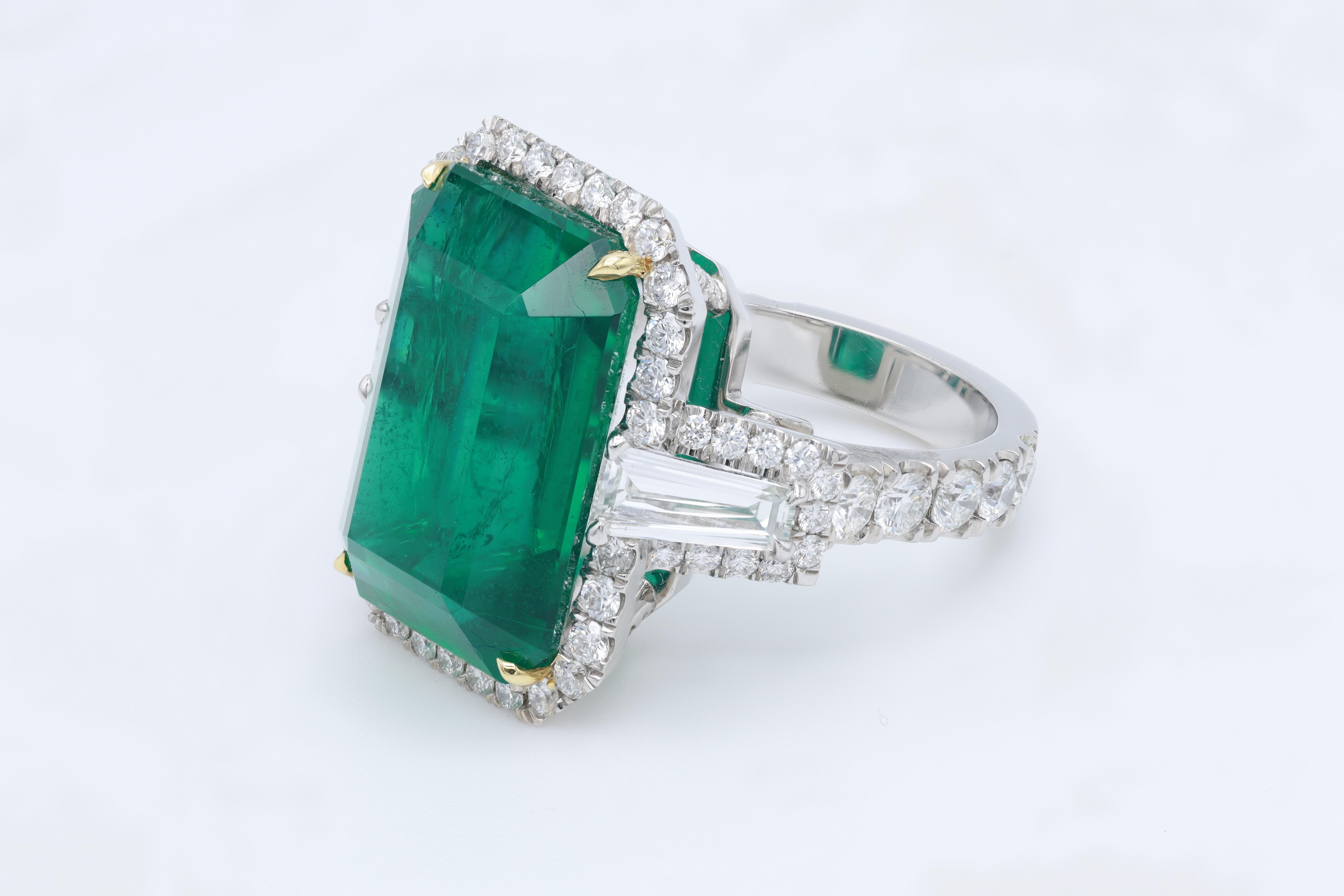 Platinum and 18 kt yellow gold emerald and diamond fashion ring featuring a 18.38 ct emerald (F1/F2-no certficate) with 3.25 cts tw of diamonds (1.08 cts tapered baguettes and 2.17 cts of round diamonds) in a halo setting.
Diana M. is a leading