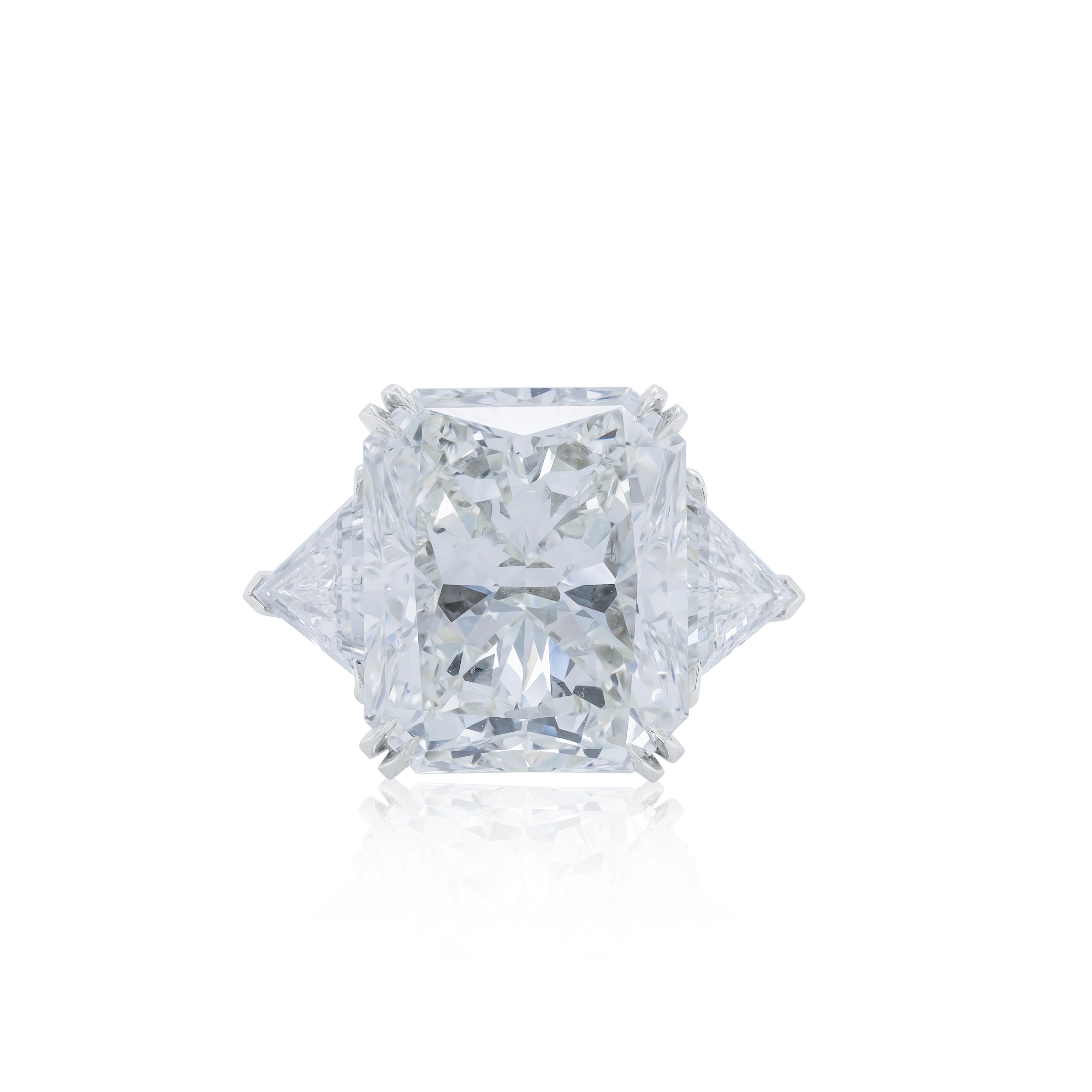 Anello di fidanzamento in platino con un diamante centrale (J-VS2) da 18,03 carati con taglio radiante e 2,75 carati di diamanti a forma di triangolo sui lati. 
Diana M è un negozio unico per tutti i tuoi acquisti di gioielli, con una linea di