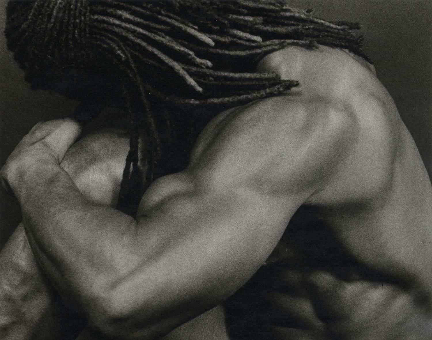 Edwin (a muscular nude male with dreadlocks flowing rests his head on a knee) - Photograph by Dianora Niccolini