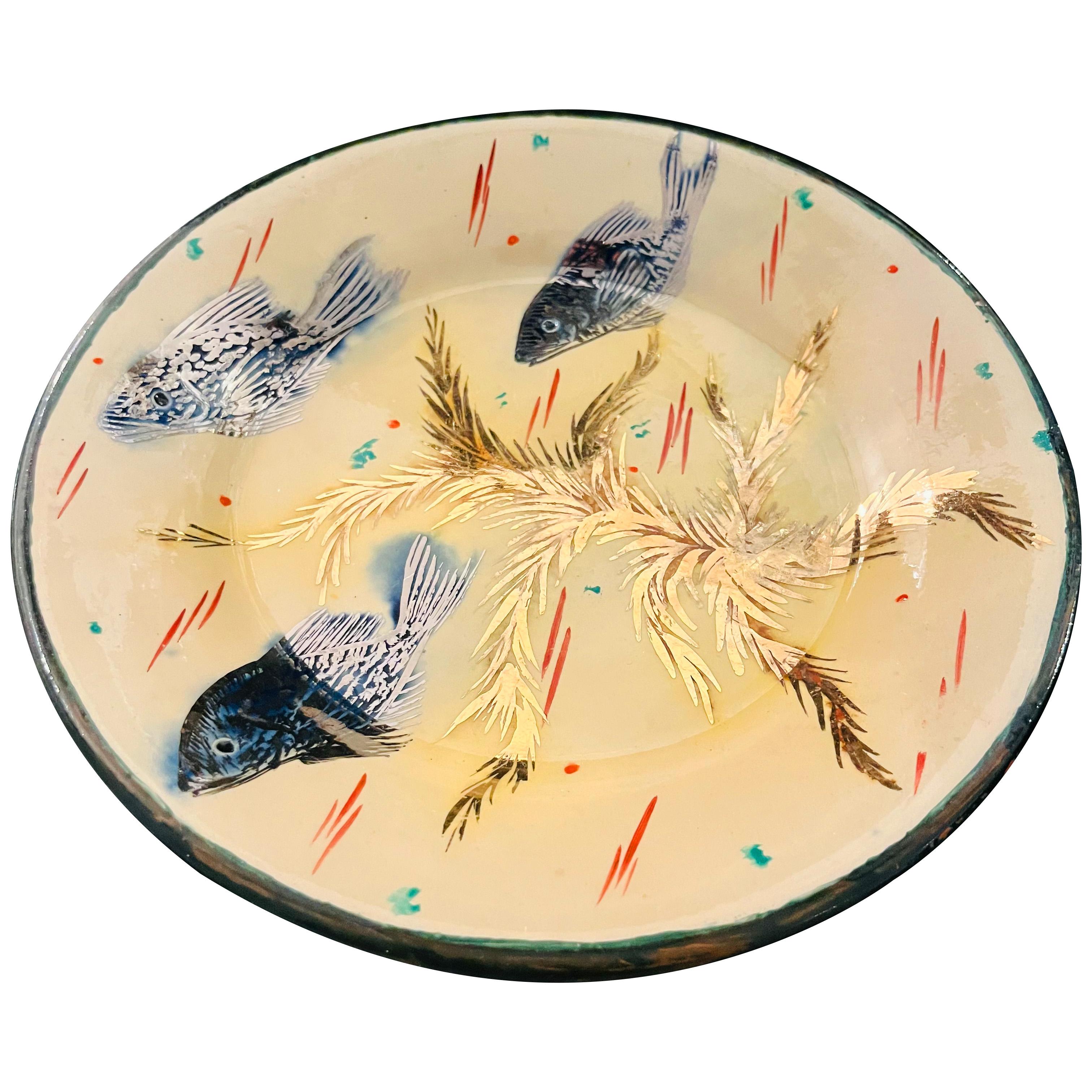Dessert plate decorated with a colourful aquatic scene, shining with the delicate gold and silver reflections of the enamel paint. Three small blue fish enhanced with silver swim around golden seaweed. These hand-drawn designs by Catalan artist