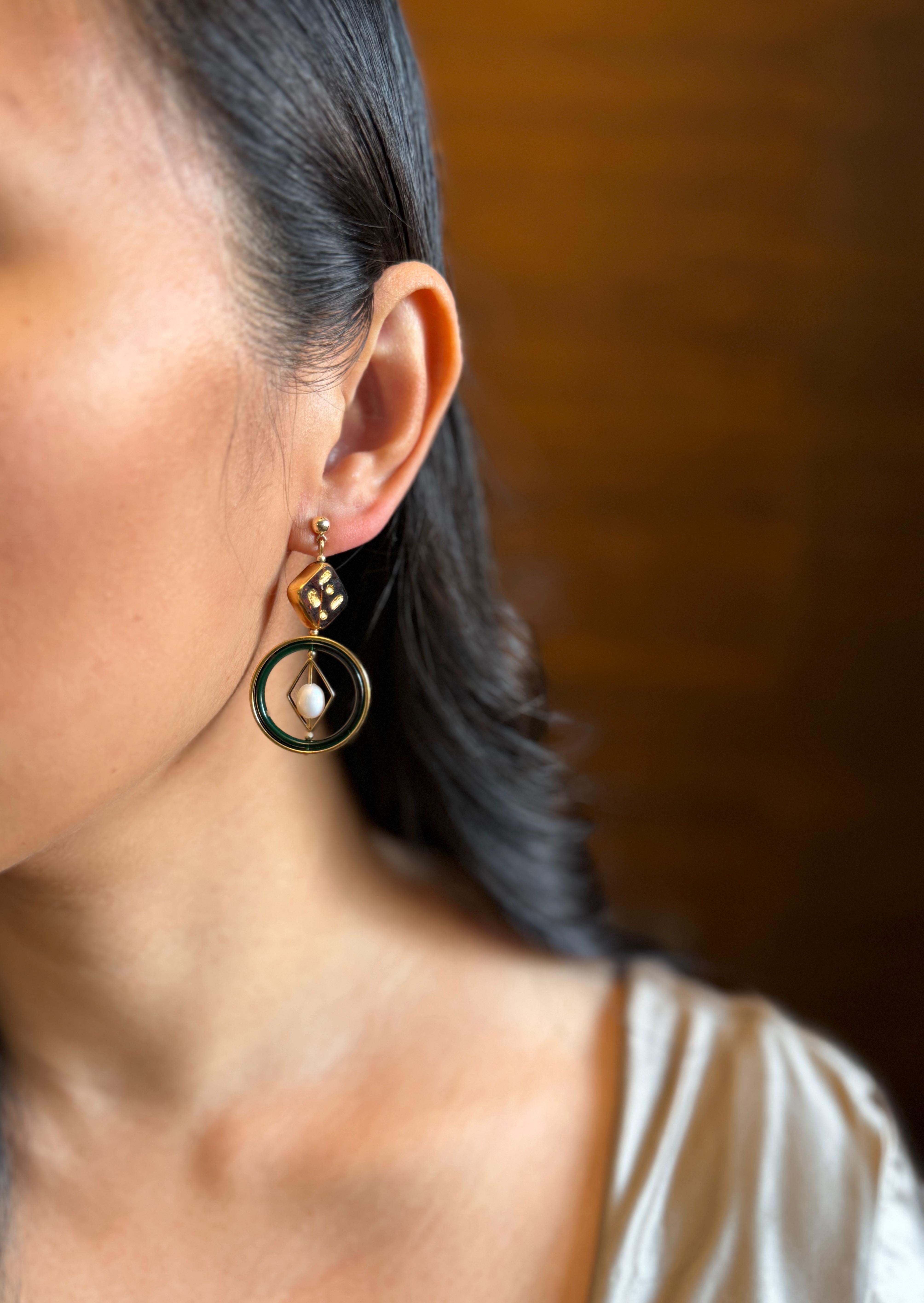Chaque boucle d'oreille est composée de perles de verre allemandes brunes bordées d'or, de lucite vintage, de perles d'eau douce, de métal en laiton plaqué d'or 24 carats, d'accessoires en or et d'un clou d'oreille. 

Les perles de verre allemandes