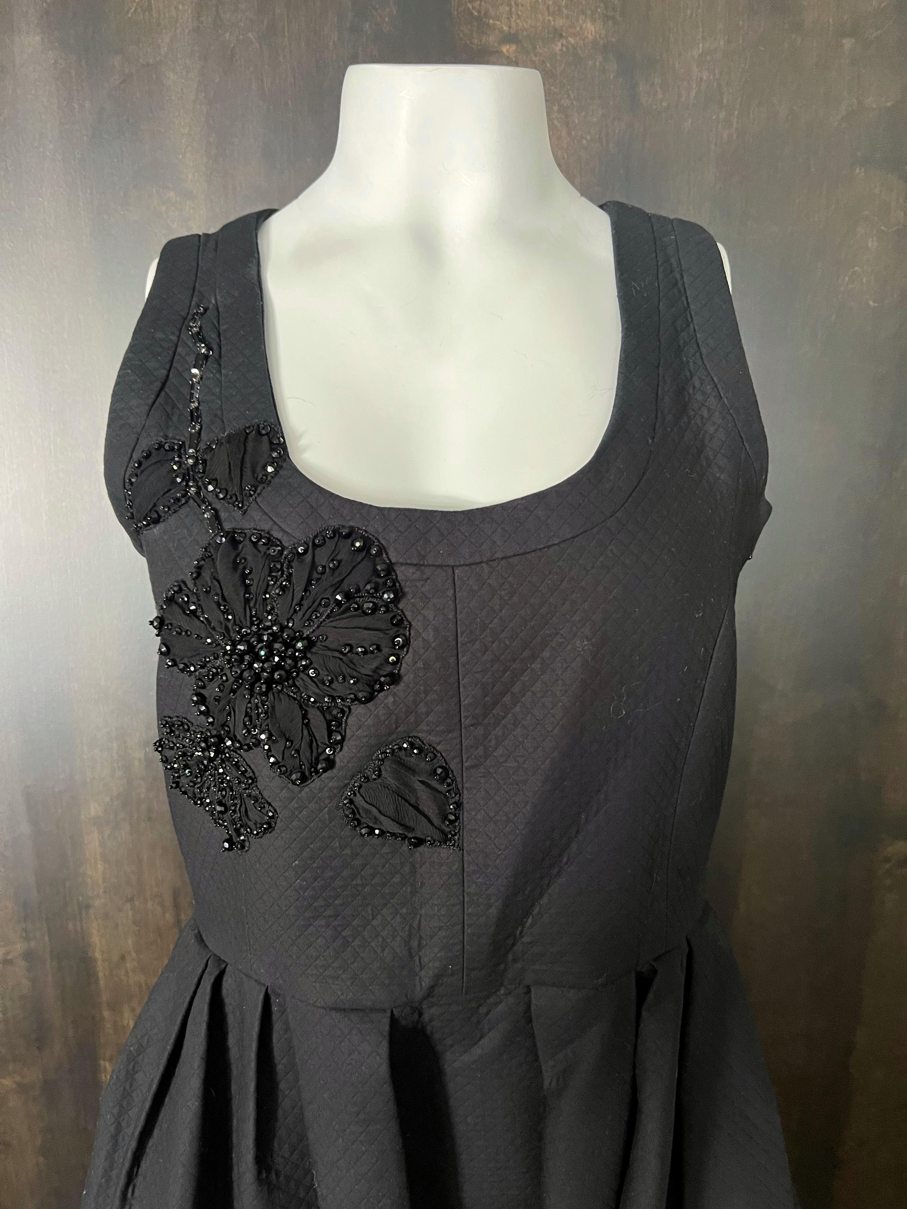 - Escote redondo
- Sin mangas
- Falda acampanada
- Diseño floral con cuentas 
