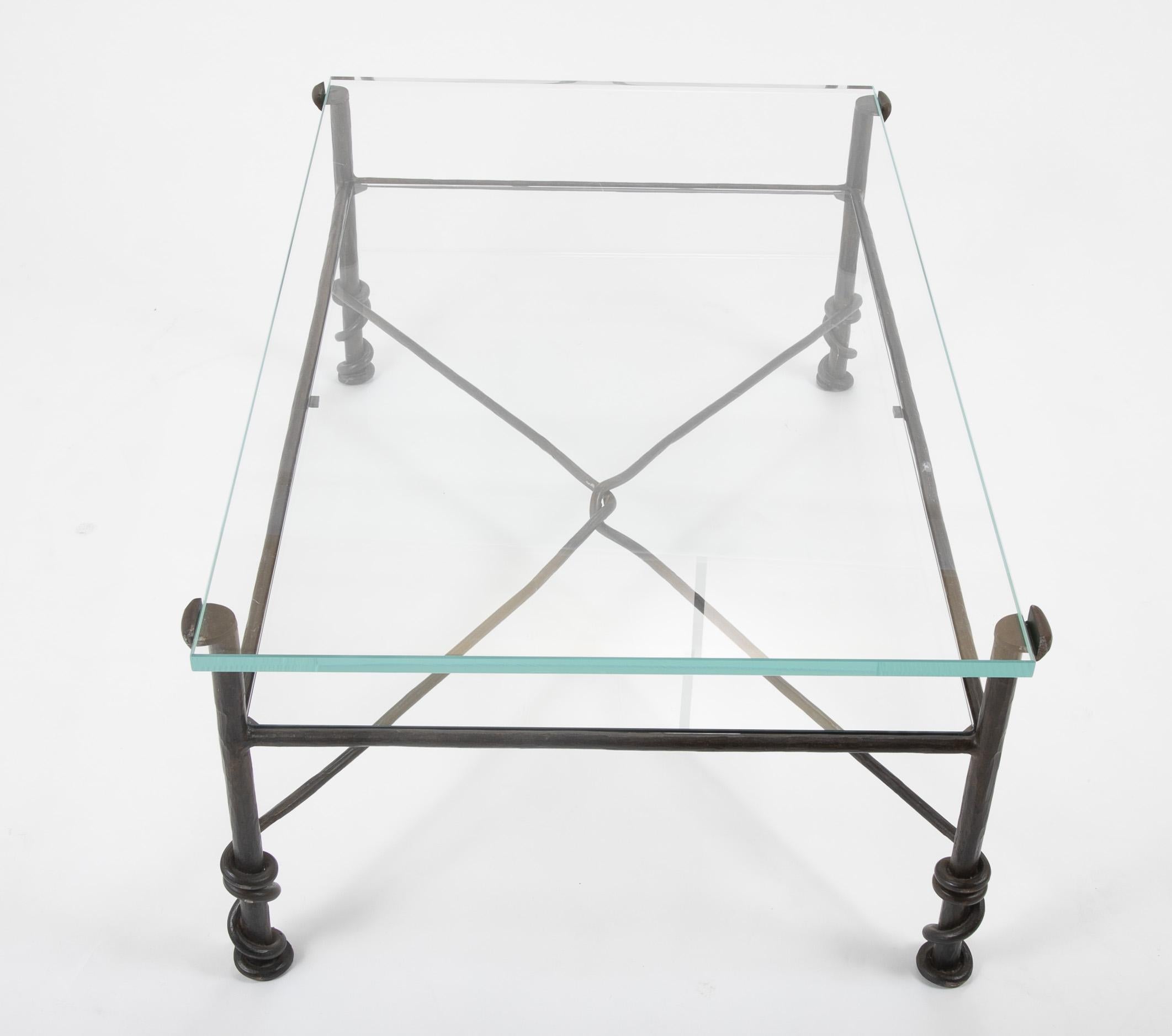 Wrought iron low table with two tiered glass top. The thick top piece resting in iron supports, the thinner second tier acts as a shelf underneath, a great place for books. With unusual rope-form iron stretchers that intertwine and wraparound the