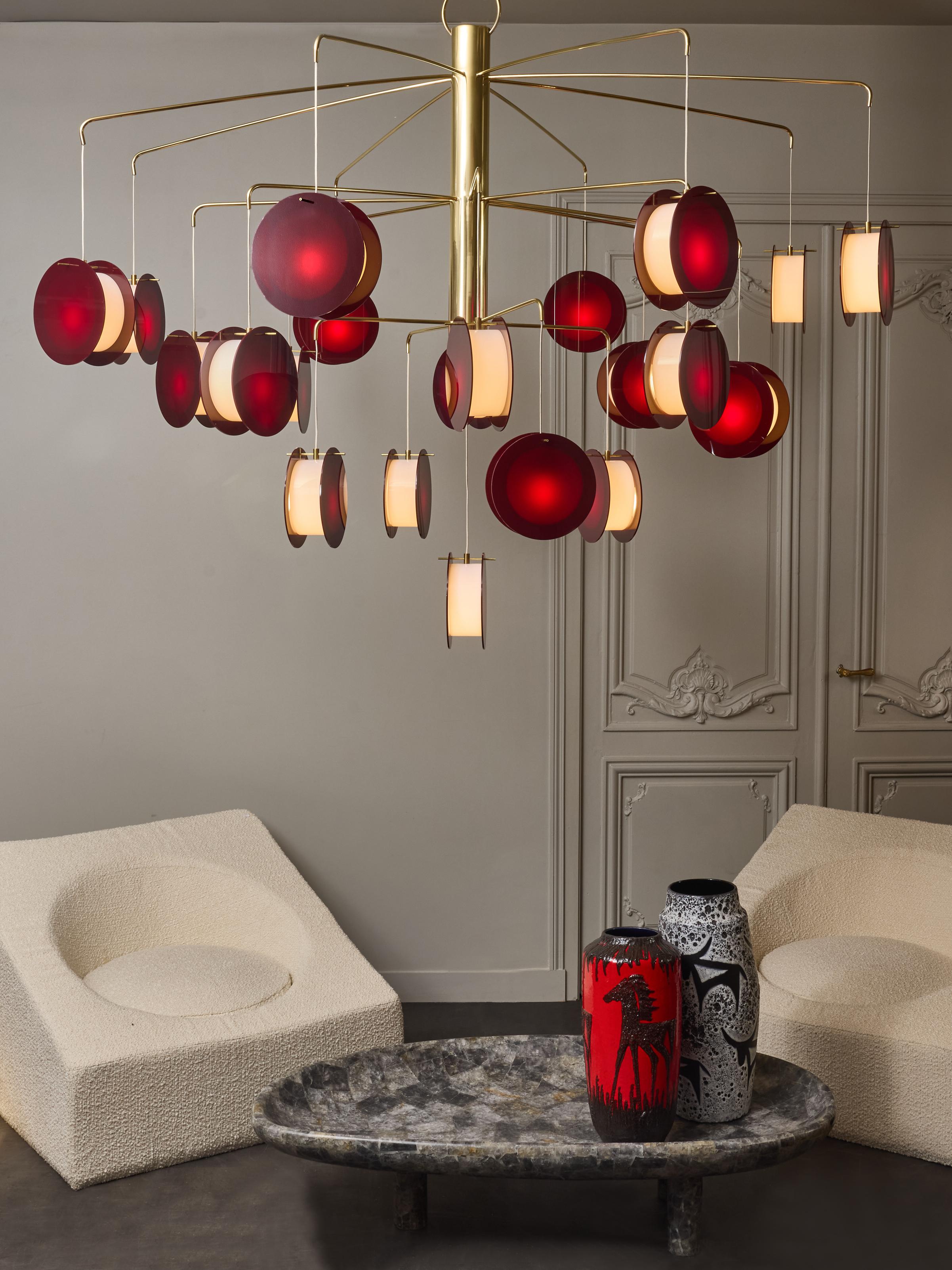 Large decorative chandelier by Diego Mardegan, made of a large brass center cylinder from where leave slightly bowing thin brass arms each holding a three parts plexi sconce diffusing the light.
The height of the chandelier can be lengthen with