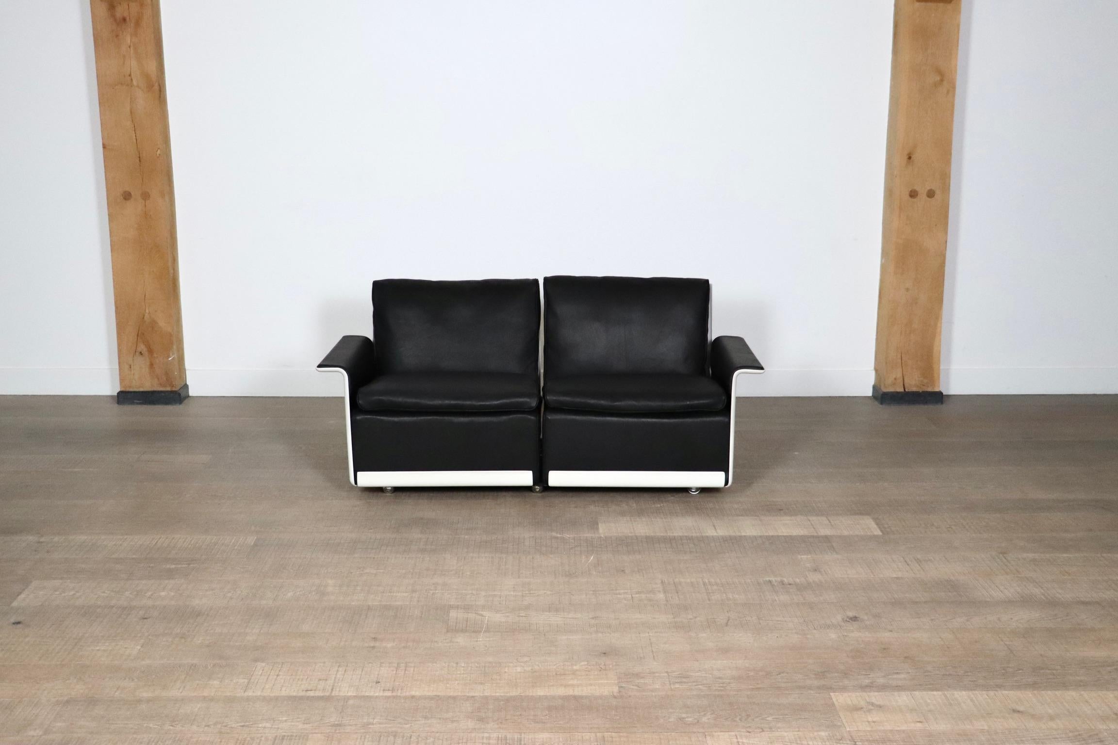 Schönes zweisitziges Sofa in schwarzem Leder von Dieter Rams für Vitsoe, Deutschland 1980er Jahre. Die weiße Außenhülle besteht aus einer heißgepressten Formmasse, die ähnlich wie Glasfaser ist, aber stärker als diese. Dieses Sofa ist aus